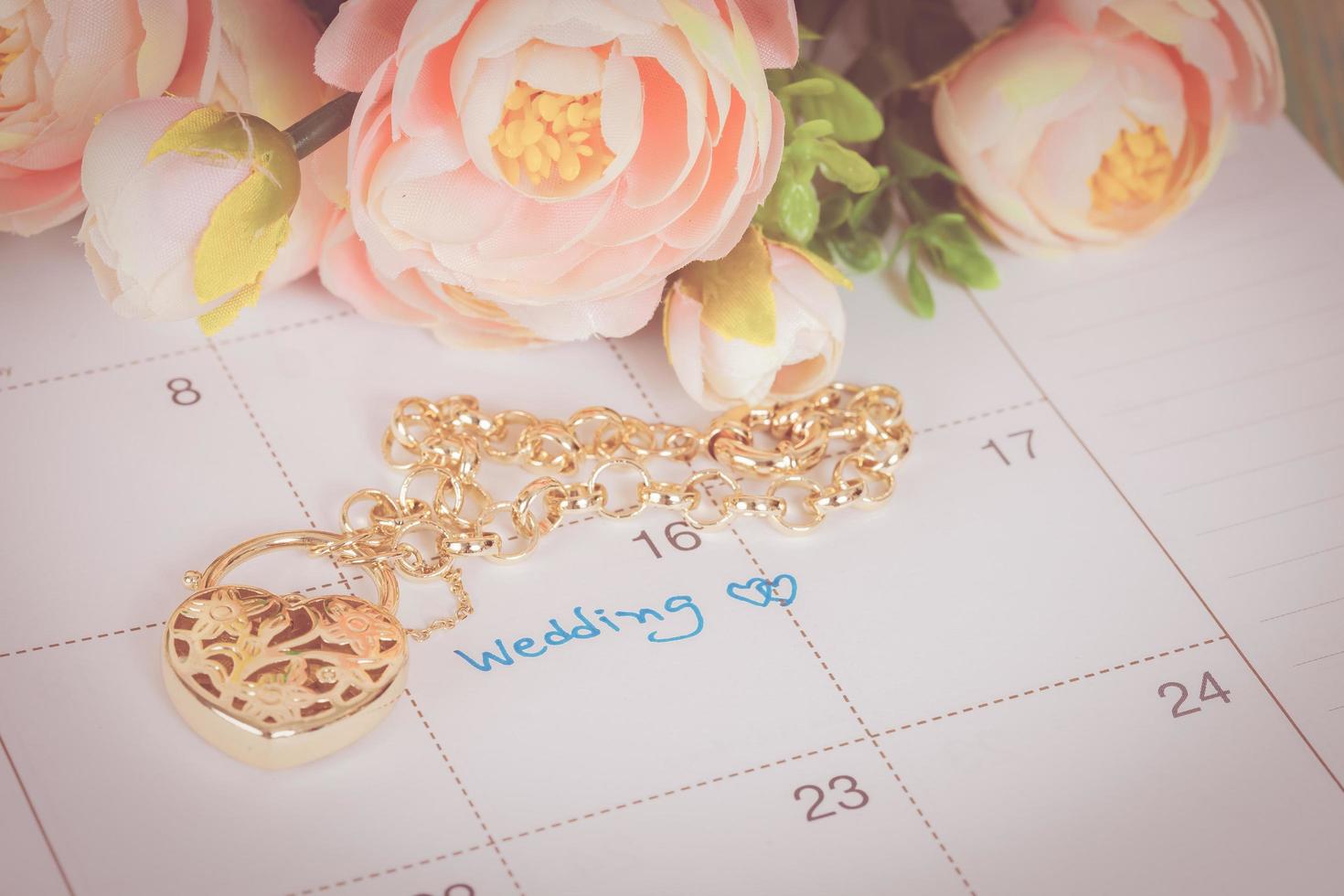 word wedding on calendar and gold bracelet with heart photo