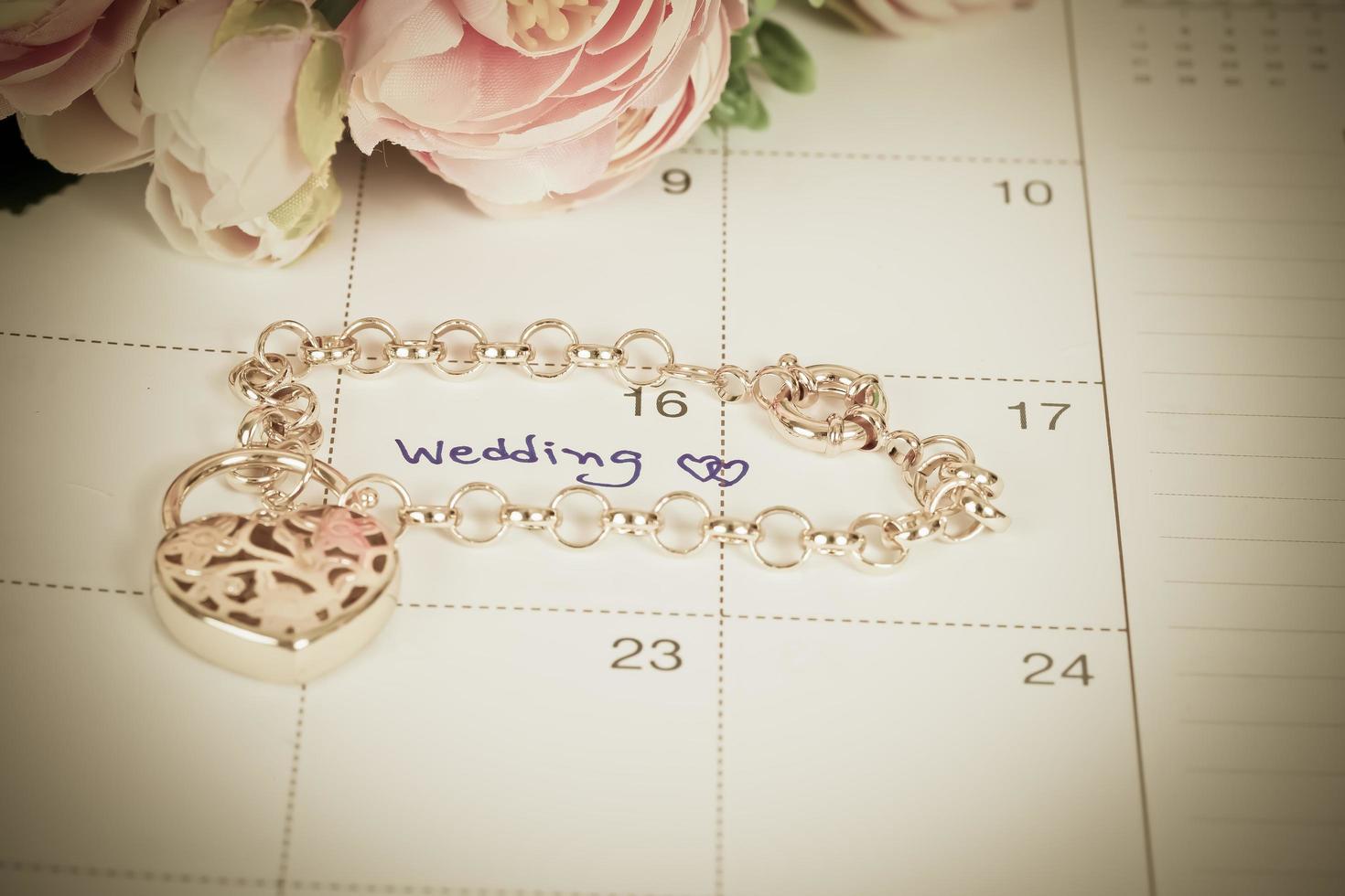 word wedding on calendar and gold bracelet with heart photo