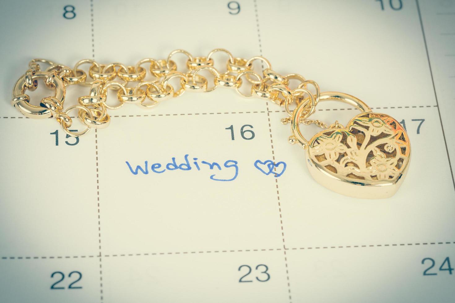 word wedding on calendar and gold bracelet with heart photo