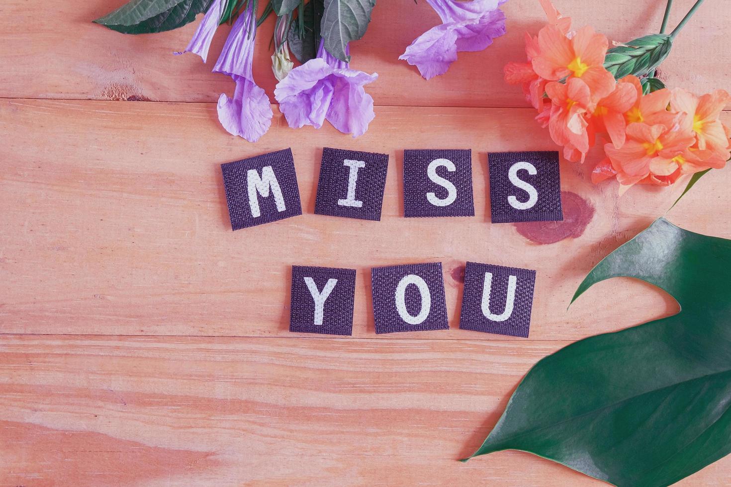 Miss you tag with flower on wood table. photo