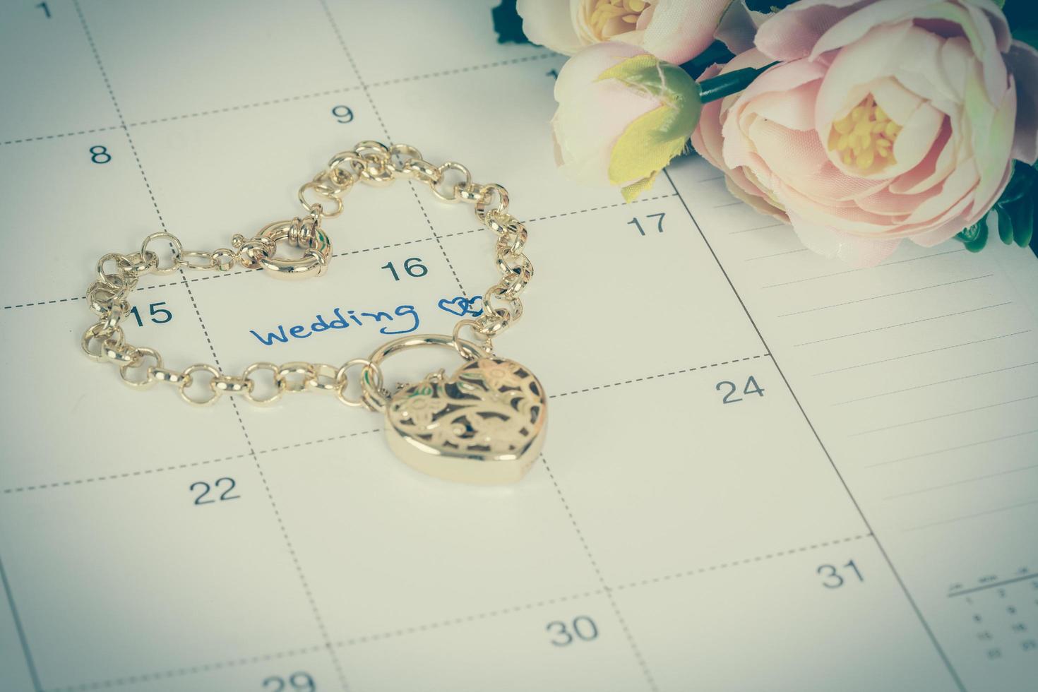 word wedding on calendar and gold bracelet with heart photo