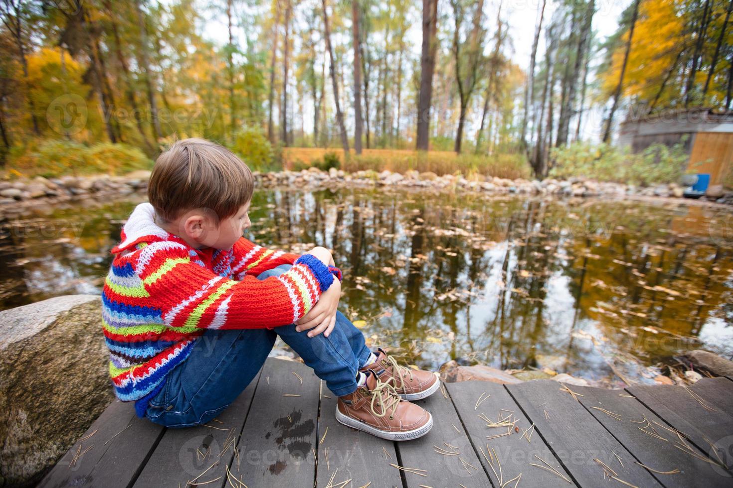 Child on an autumn walk. The boy walks on a background of autumn nature. photo