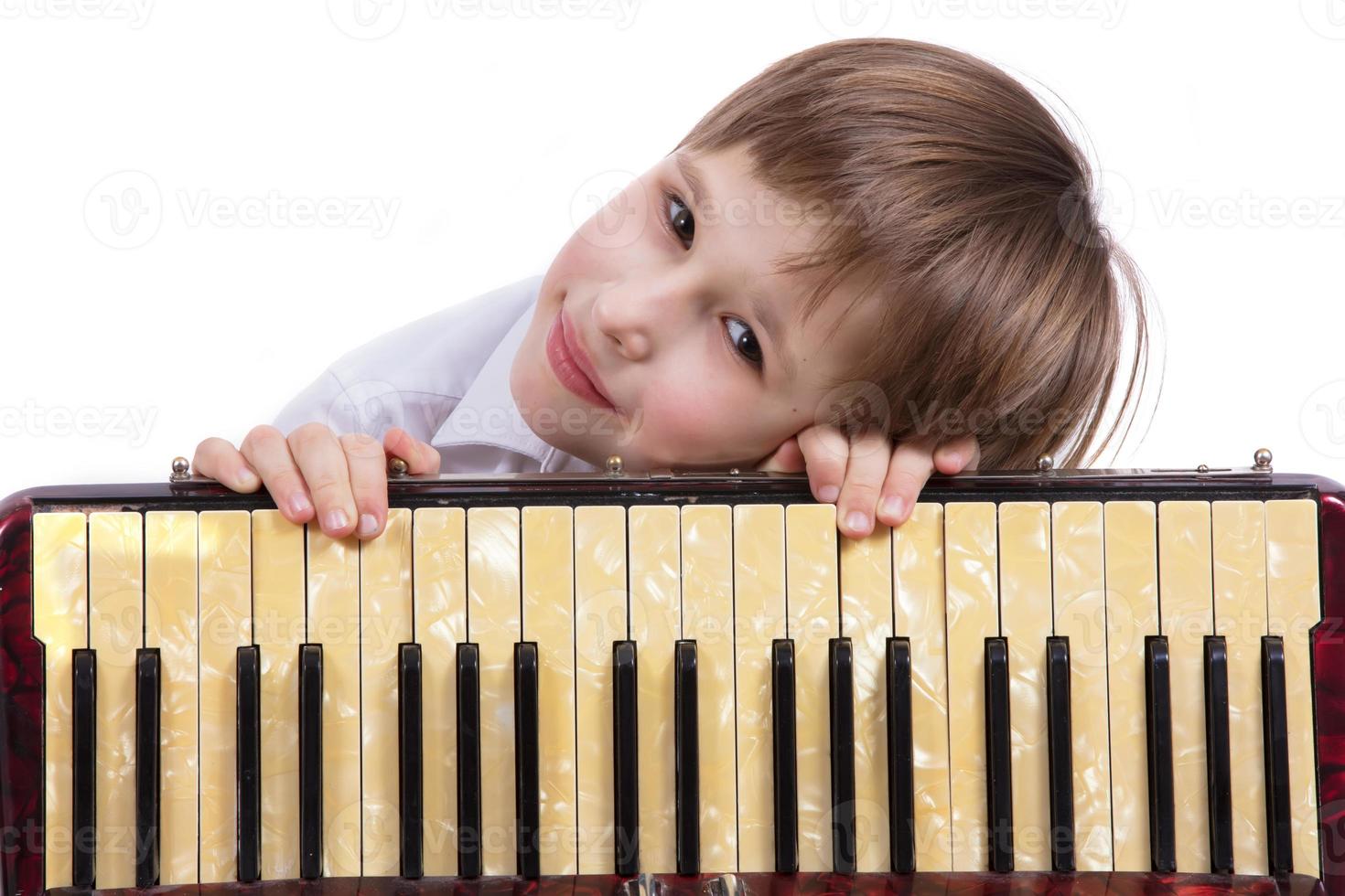 Child with a musical instrument. Elementary age boy with an accordion. photo