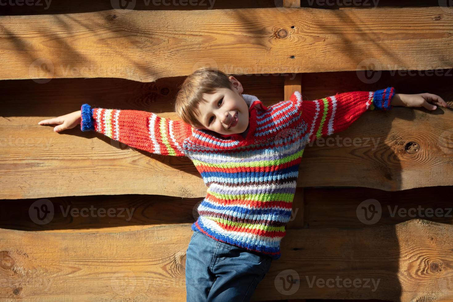 Beautiful baby in nature. Elementary age boy on the background of a wooden fence. Autumn walk of the child. photo