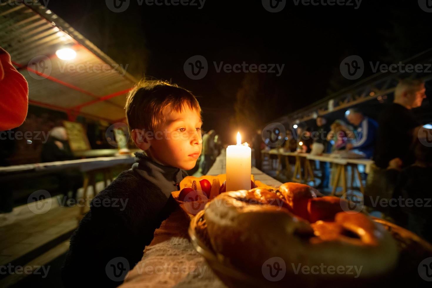 niño en Pascua de Resurrección noche con un rodar y un vela en el cementerio. foto