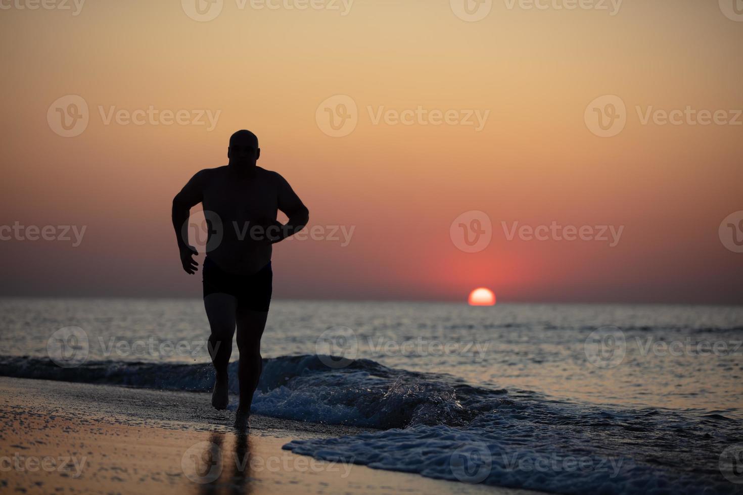 Silhouette of a male athlete on a background of sunrise at sea photo