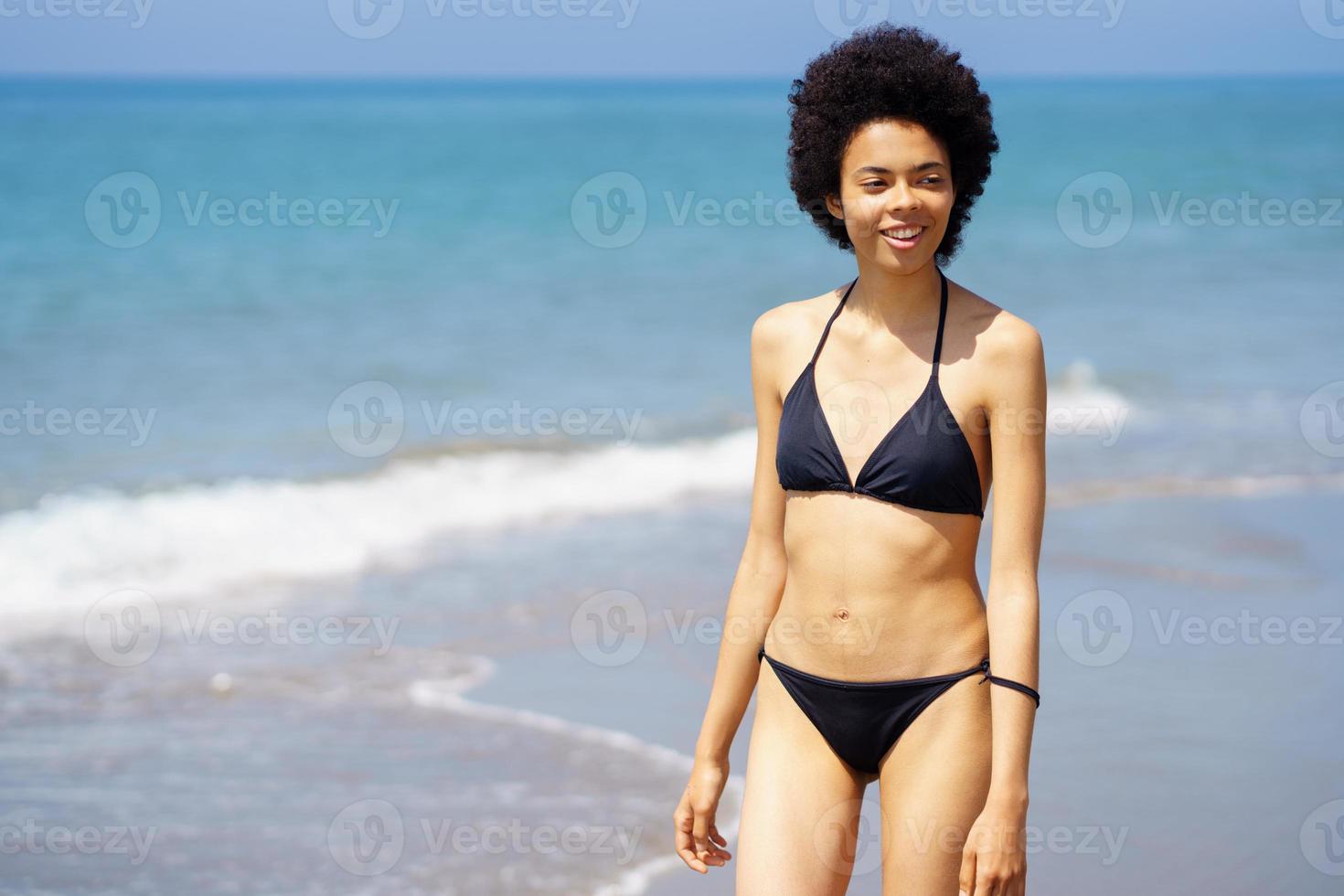 contenido negro mujer en bikini caminando en costa foto