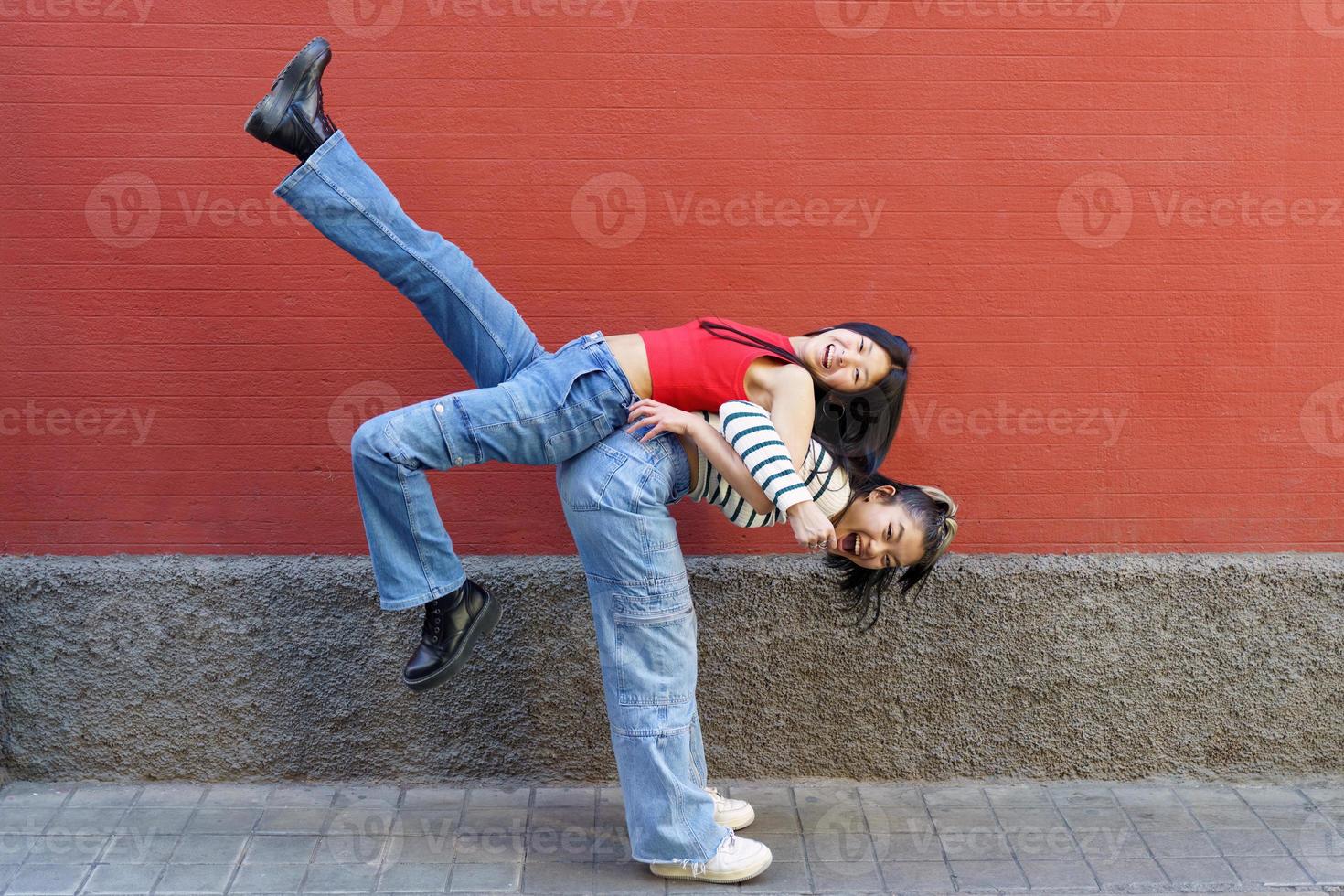 Happy Asian female lifting friend on back photo