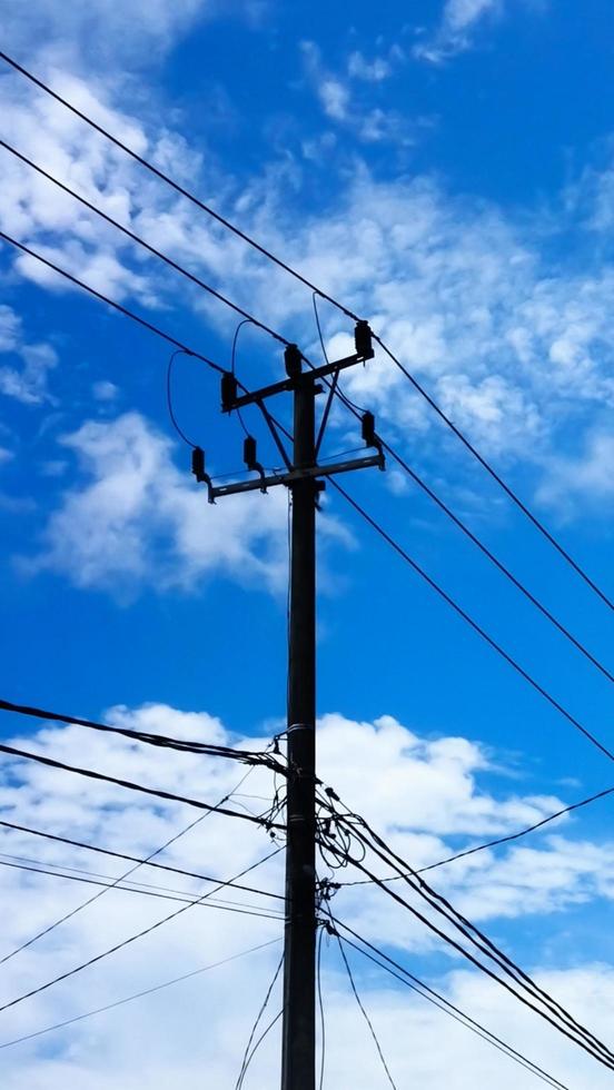 Electric pole in front of the house with bright clouds as a background. photo