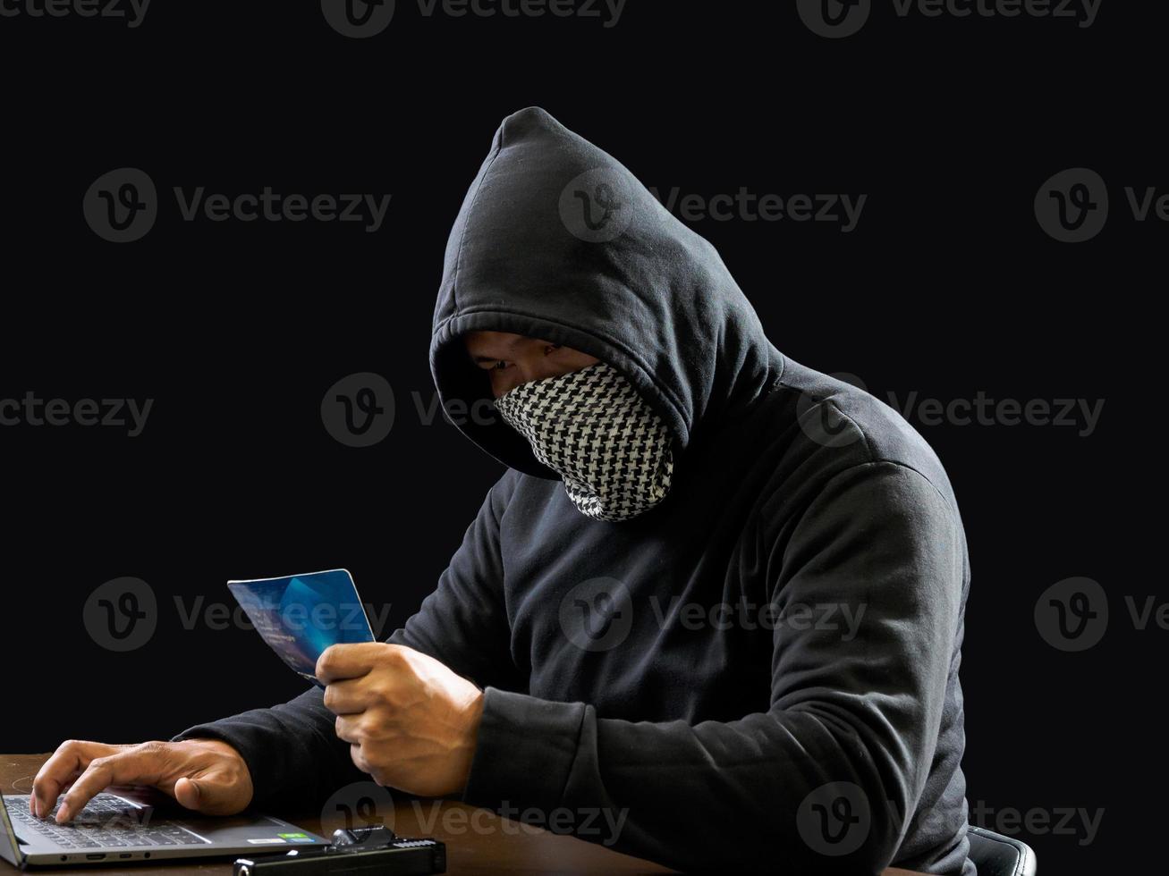 Hacker spy man one person in black hoodie sitting on a table looking computer laptop used login password attack security to circulate data digital in internet network system, night dark background. photo