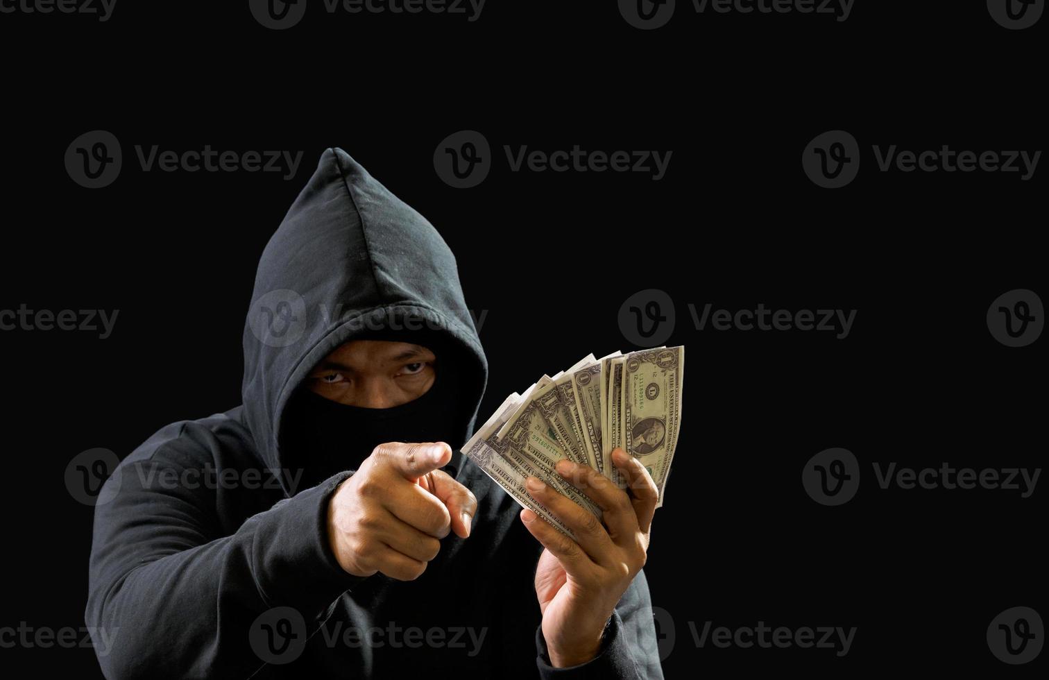 Hacker spy man hands wearing a black shirt, sitting on a chair and a table, is a thief, holding money, counting the amount obtained from hijacking or robbing, in a pitch-black room. photo