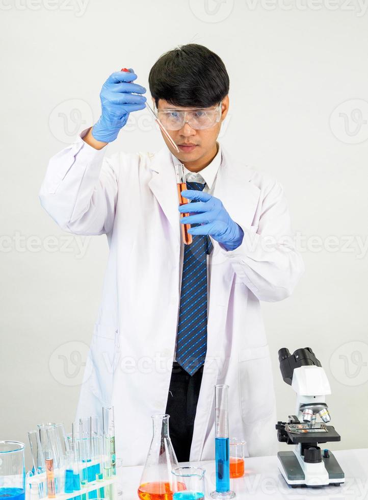Asian man student scientist or doctor look hand holding in reagent mixing laboratory In a science research laboratory with test tubes of various sizes in  laboratory chemistry lab white background. photo