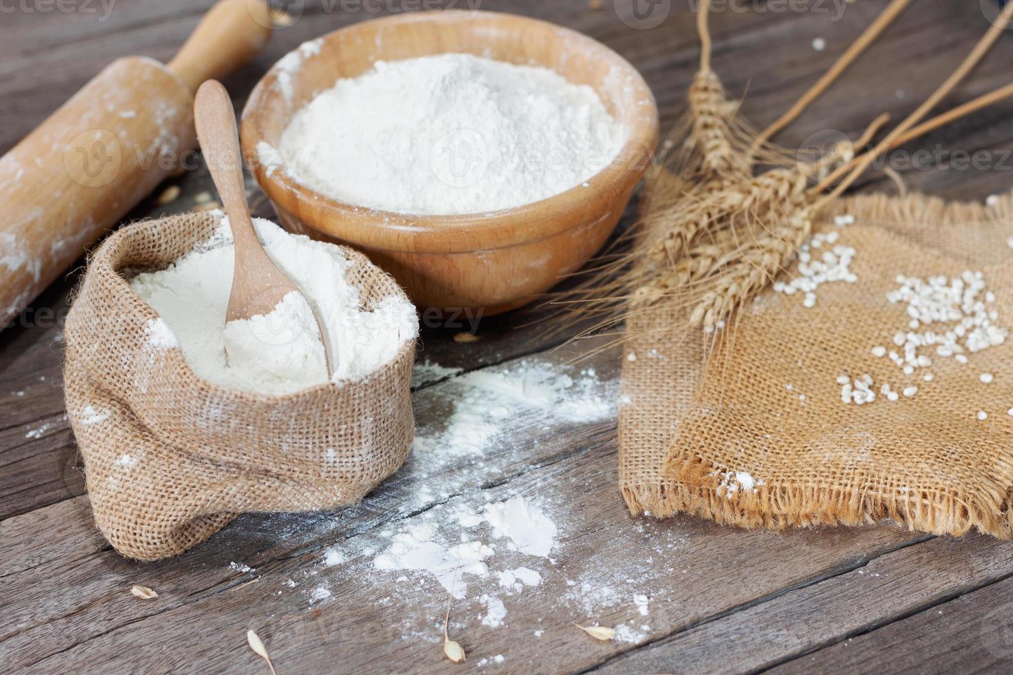 Soft focus, flour in bags, ears of wheat, barley, cooking, bread, and cookies arranged on a wooden tabletop in a rustic kitchen, top view. photo