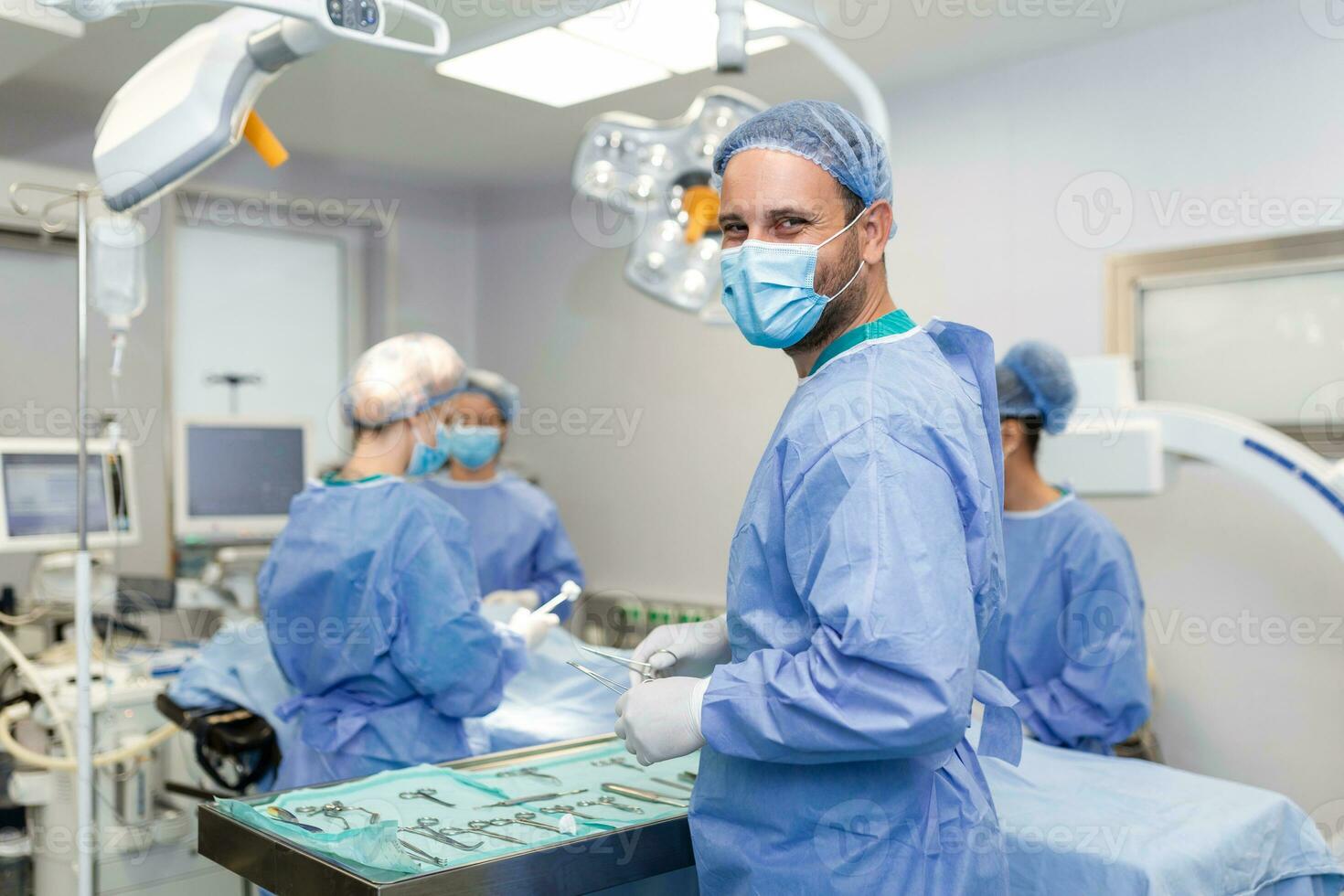 Portrait of happy man surgeon standing in operating room, ready to work on a patient. Male medical worker in surgical uniform in operation theater. photo