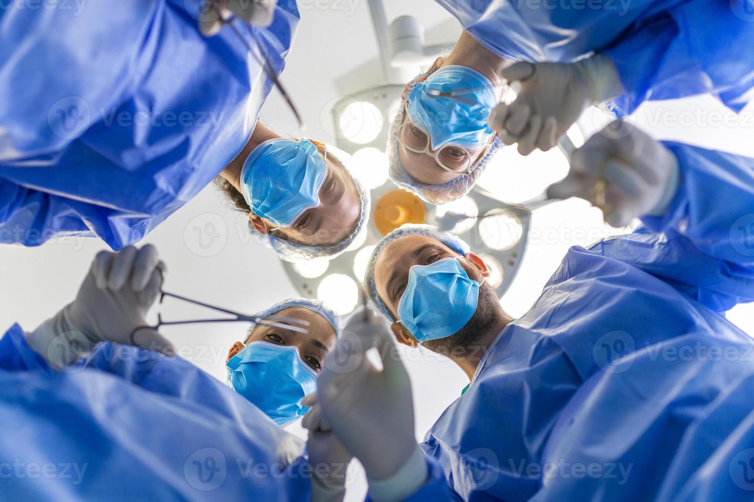 Surgeons standing above of the patient before surgery. Multi-ethnic healthcare workers performing surgery on patient at operation theater. photo