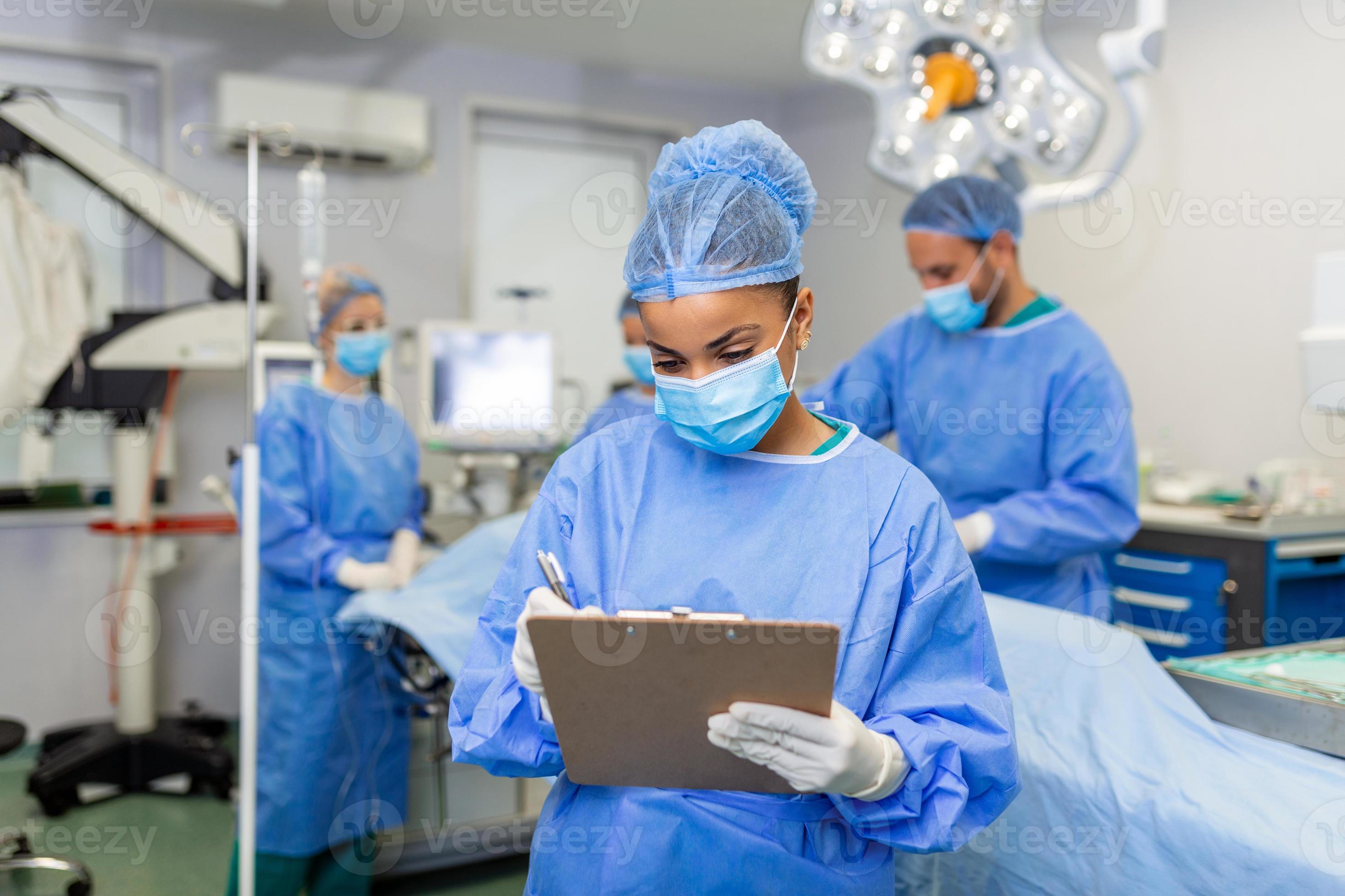 Surgeon writing on clipboard in operation room, anaesthesiologist 