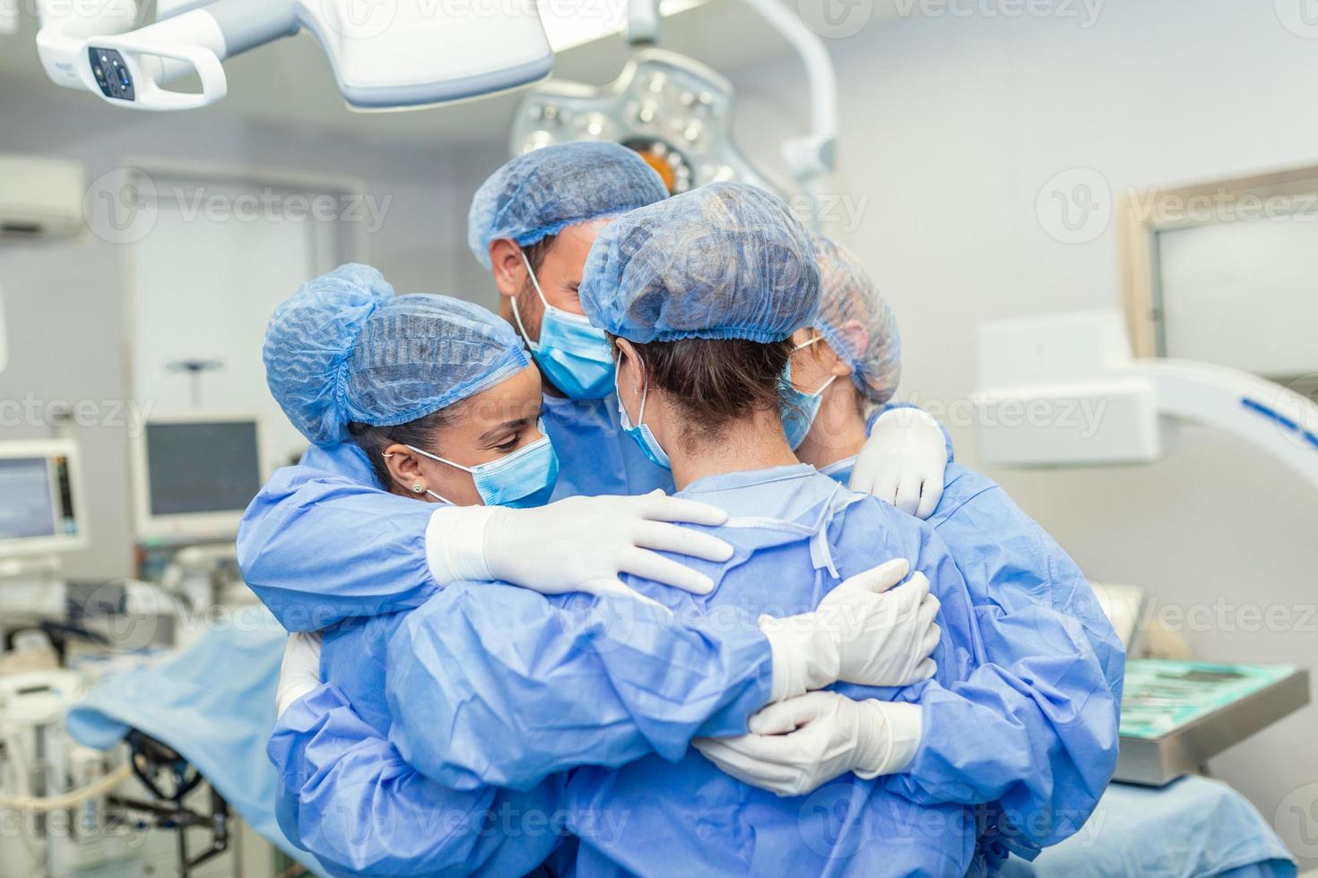 Medical professionals embracing each other in ICU. Doctors and nurses are in protective coveralls after successful treatment. They are at hospital during COVID-19. photo