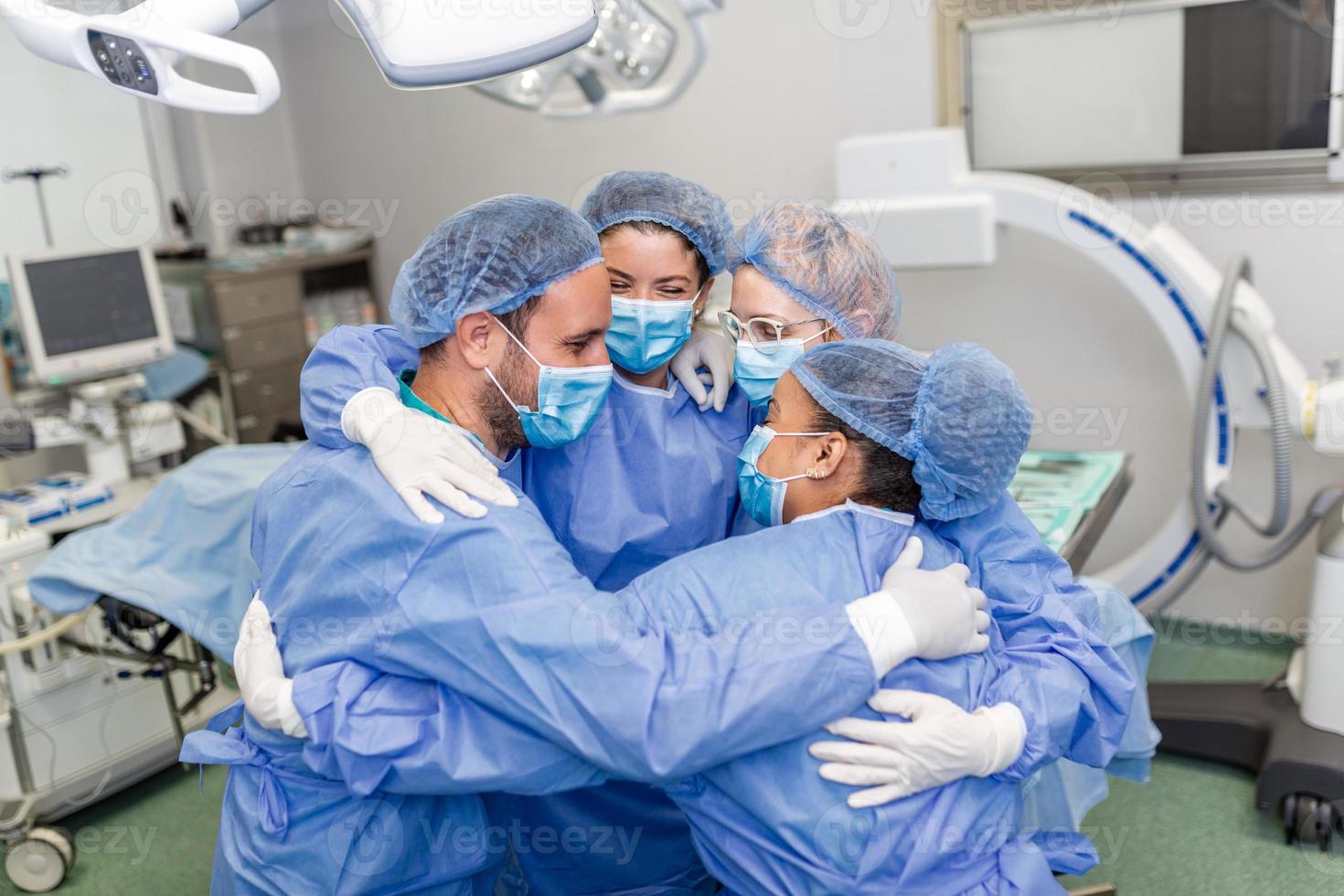 Partial view of hard-working male and female hospital team in full protective wear standing together in group embrace photo