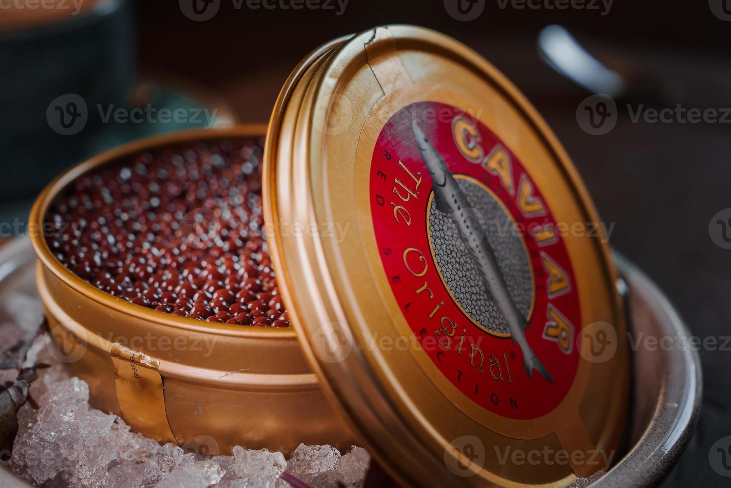 Black caviar in can placed on a plate with ice. photo