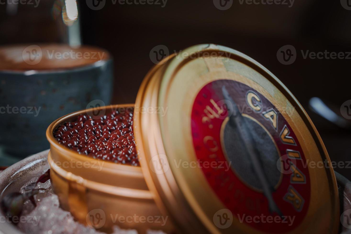 Black caviar in can placed on a plate with ice. photo