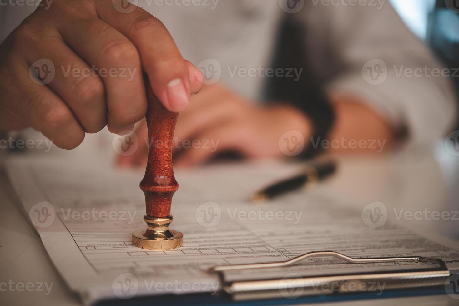 hombre de negocios estampado a mano aprobado en el contrato de documento de certificado en la oficina. abogado que sella el permiso en el papeleo en el escritorio de madera. foto