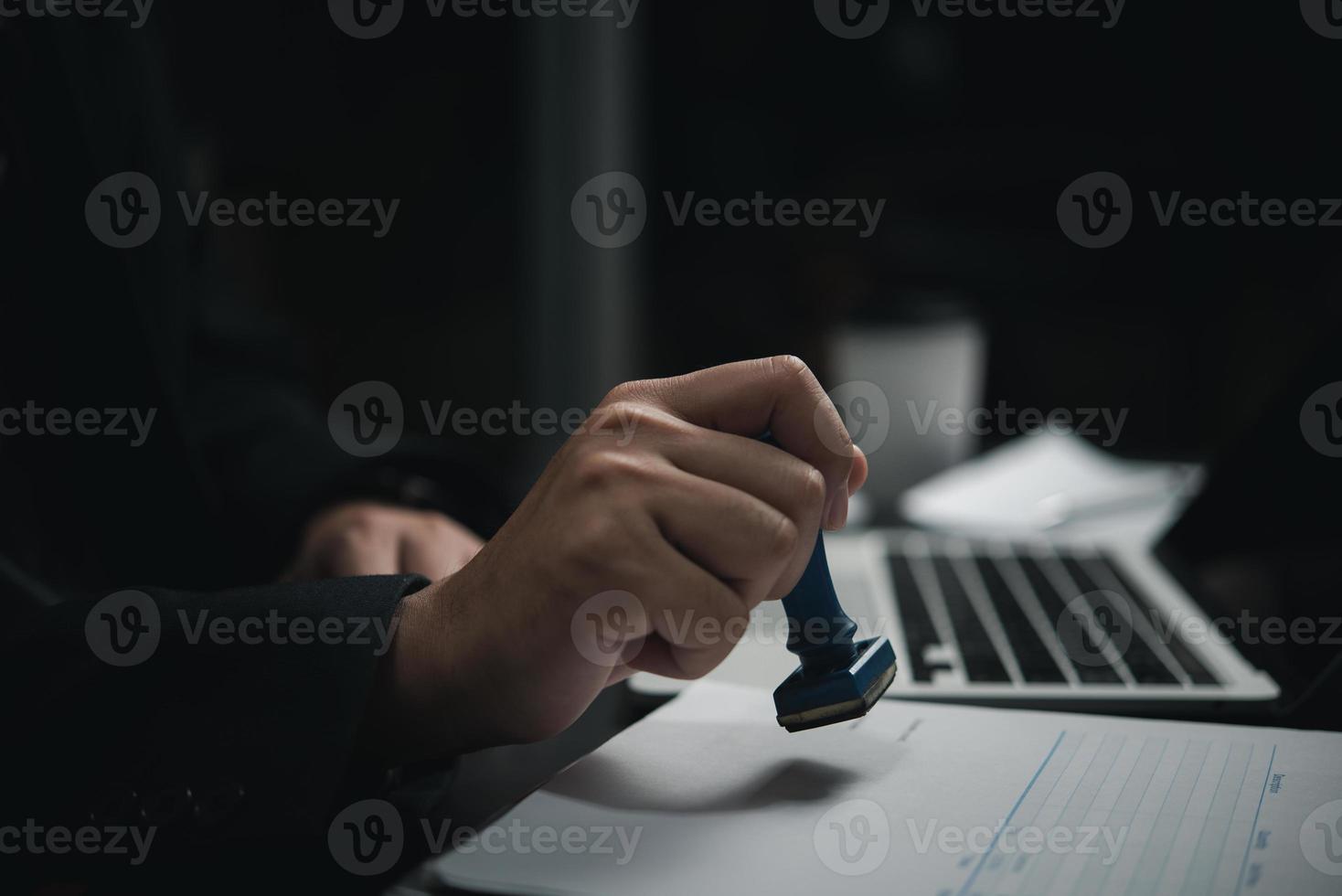 Man hand stamping approval signing on document or paperwork contract at desk. photo
