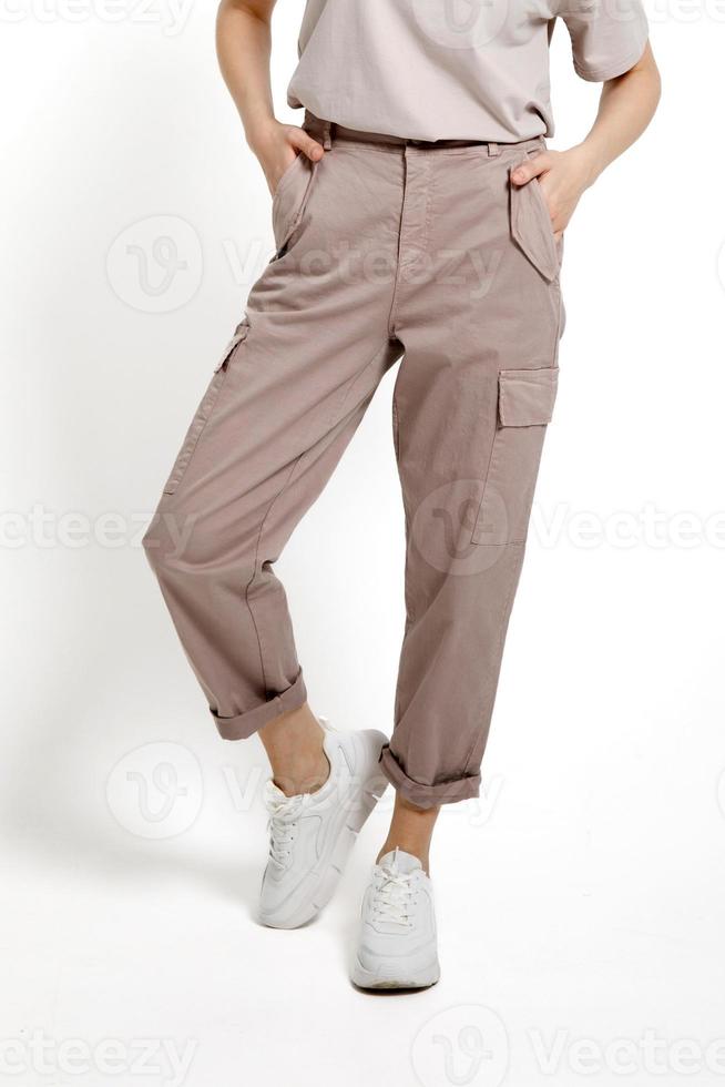 De las mujeres beige pantalones con blanco zapatillas en un blanco antecedentes. foto