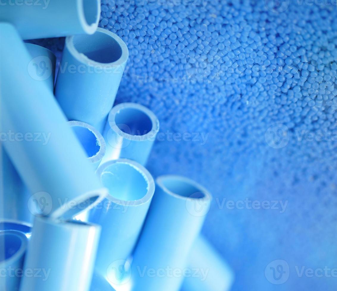 Blue pipe and plastic polymer pellets raw material for blue pvc pipe production. Industrial plastic resin. Chemical polymer granules. Thermoplastic. Plastic from petrochemical and compound extrusion. photo