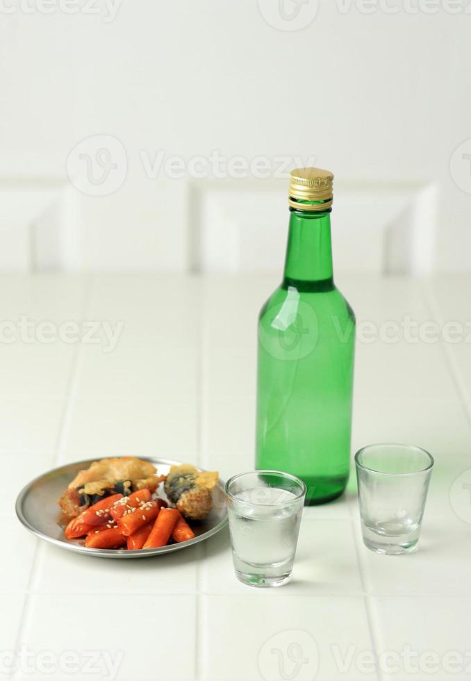 soju botella y lado plato alimento, topokki y papas fritas foto