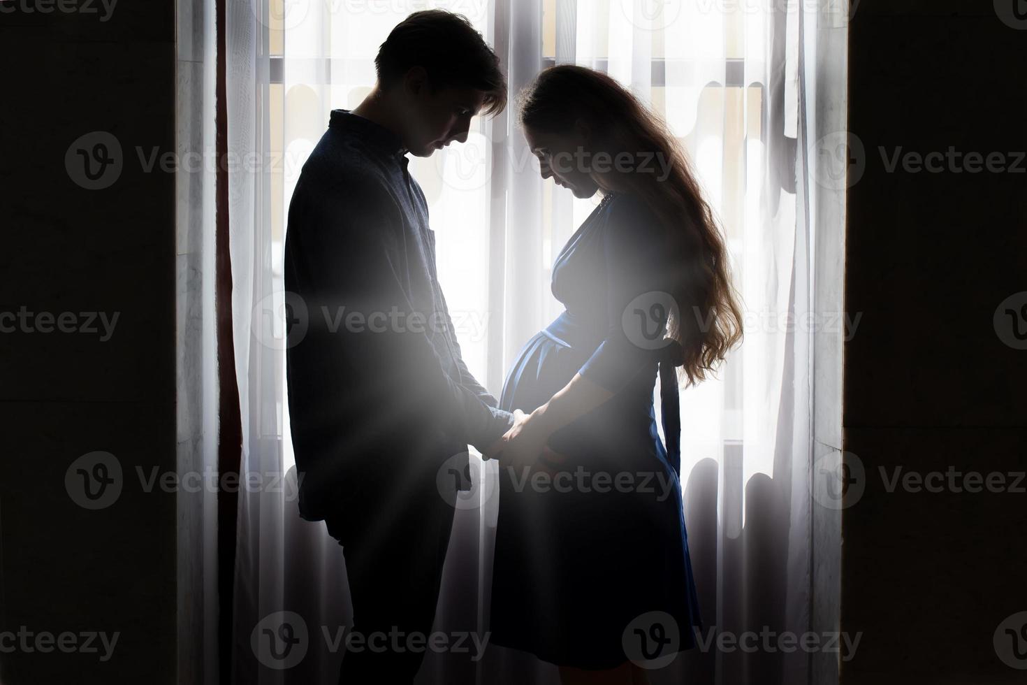 Silhouette of a pregnant woman and husband. photo