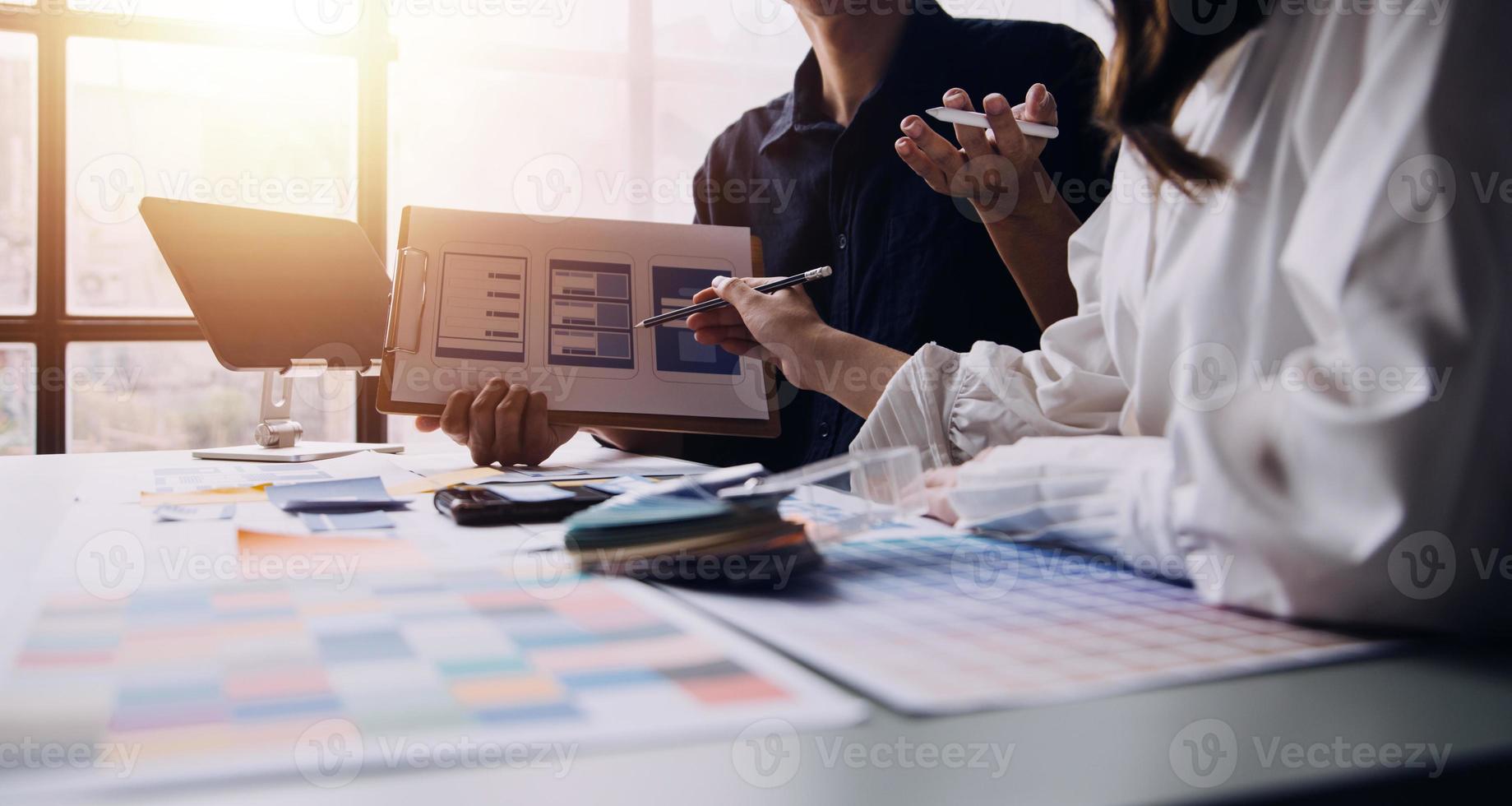 Close up ux developer and ui designer brainstorming about mobile app interface wireframe design on table with customer breif and color code at modern office.Creative digital development agency photo