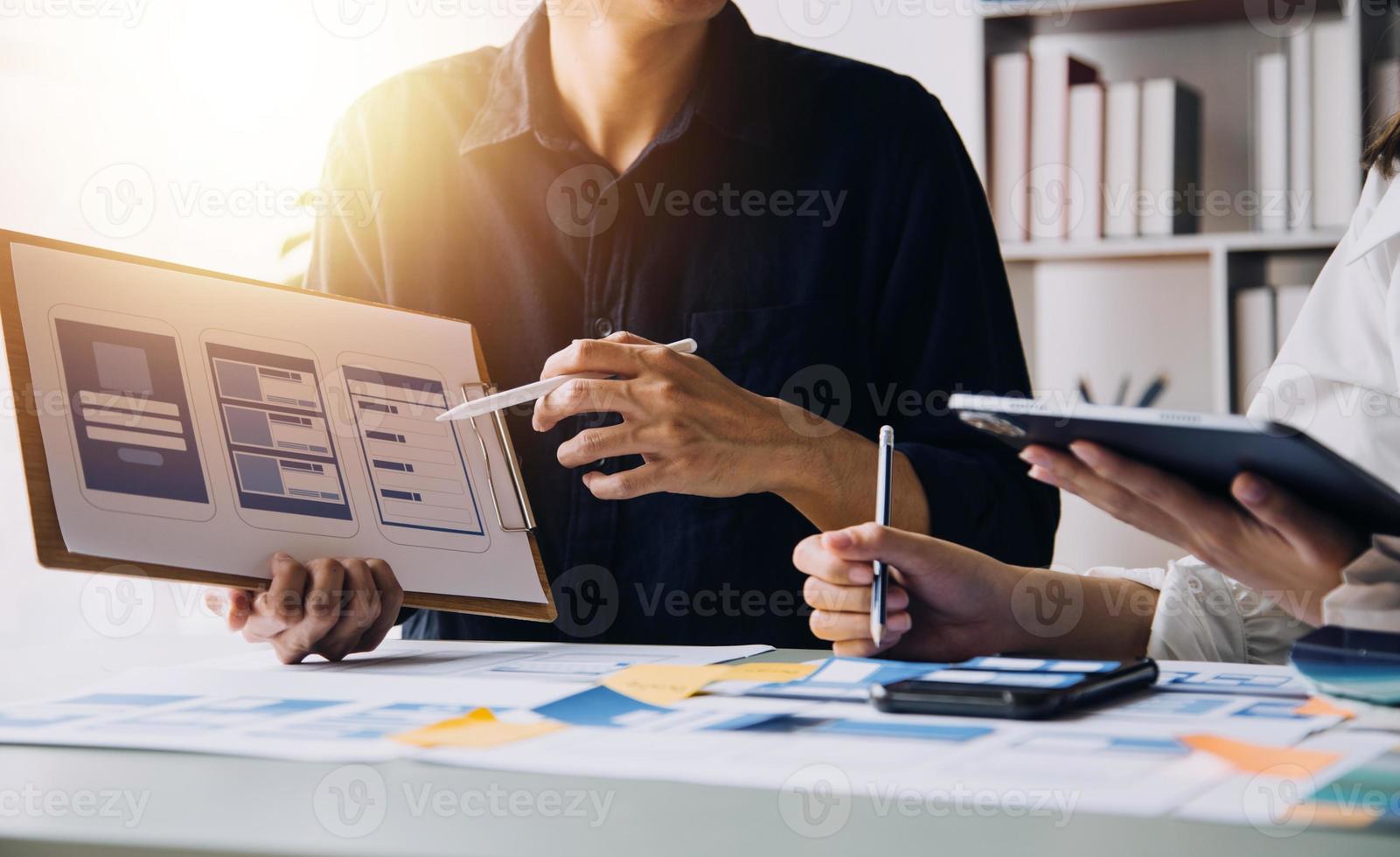 Close up ux developer and ui designer brainstorming about mobile app interface wireframe design on table with customer breif and color code at modern office.Creative digital development agency photo