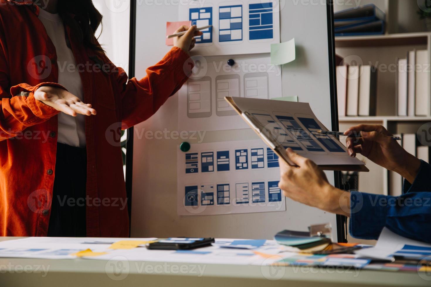 Close up ux developer and ui designer brainstorming about mobile app interface wireframe design on table with customer breif and color code at modern office.Creative digital development agency photo