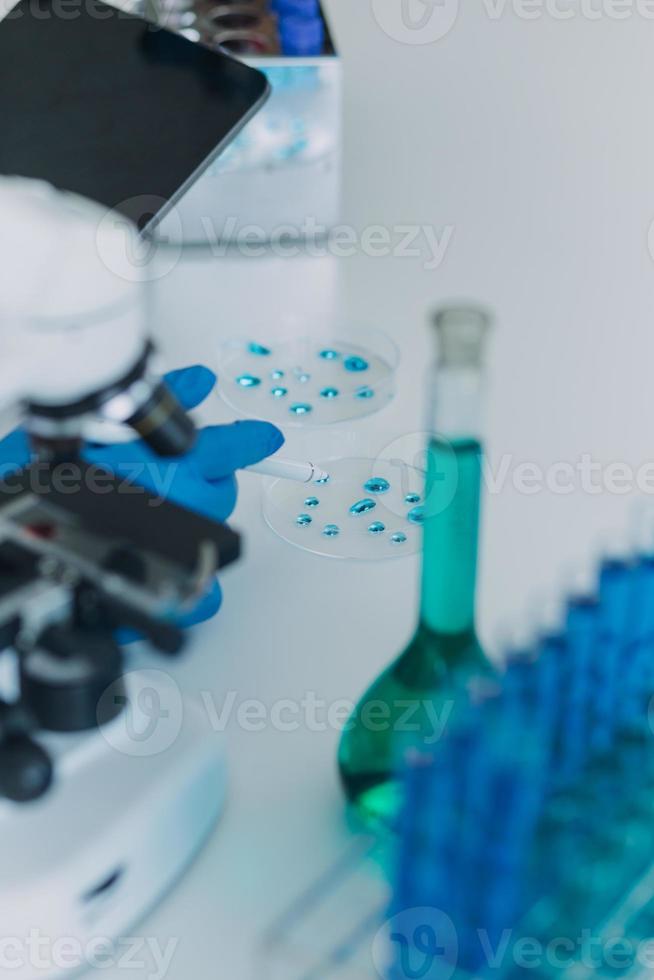 equipo científico de investigación bioquímica que trabaja con microscopio para el desarrollo de vacunas contra el coronavirus en laboratorios de investigación farmacéutica, enfoque selectivo foto