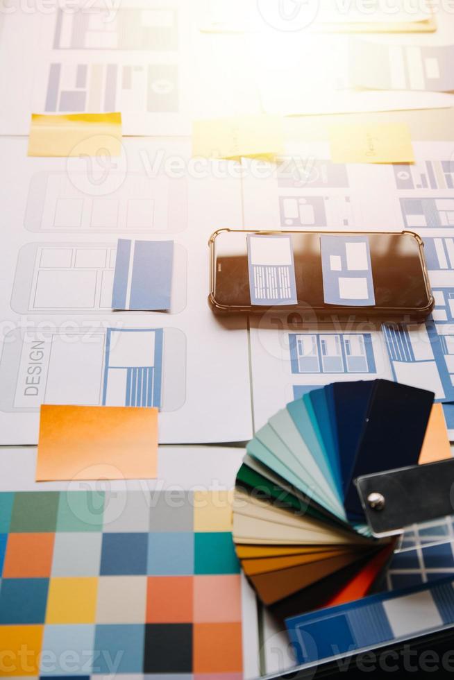 Close up ux developer and ui designer brainstorming about mobile app interface wireframe design on table with customer breif and color code at modern office.Creative digital development agency photo