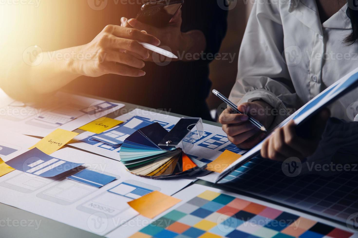 Close up ux developer and ui designer brainstorming about mobile app interface wireframe design on table with customer breif and color code at modern office.Creative digital development agency photo