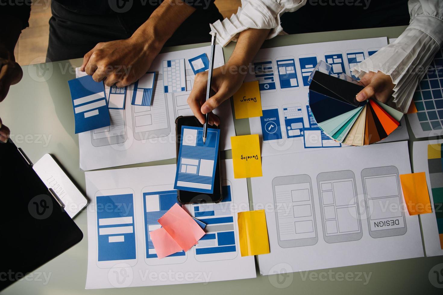 Close up ux developer and ui designer brainstorming about mobile app interface wireframe design on table with customer breif and color code at modern office.Creative digital development agency photo