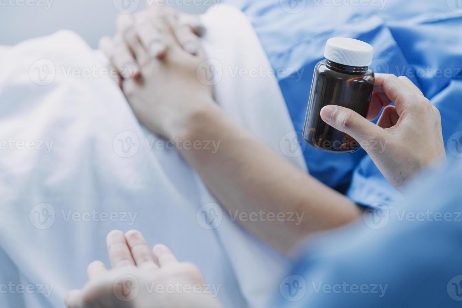 Side view of diverse doctors examining Asian female patient in bed in ward at hospital. photo