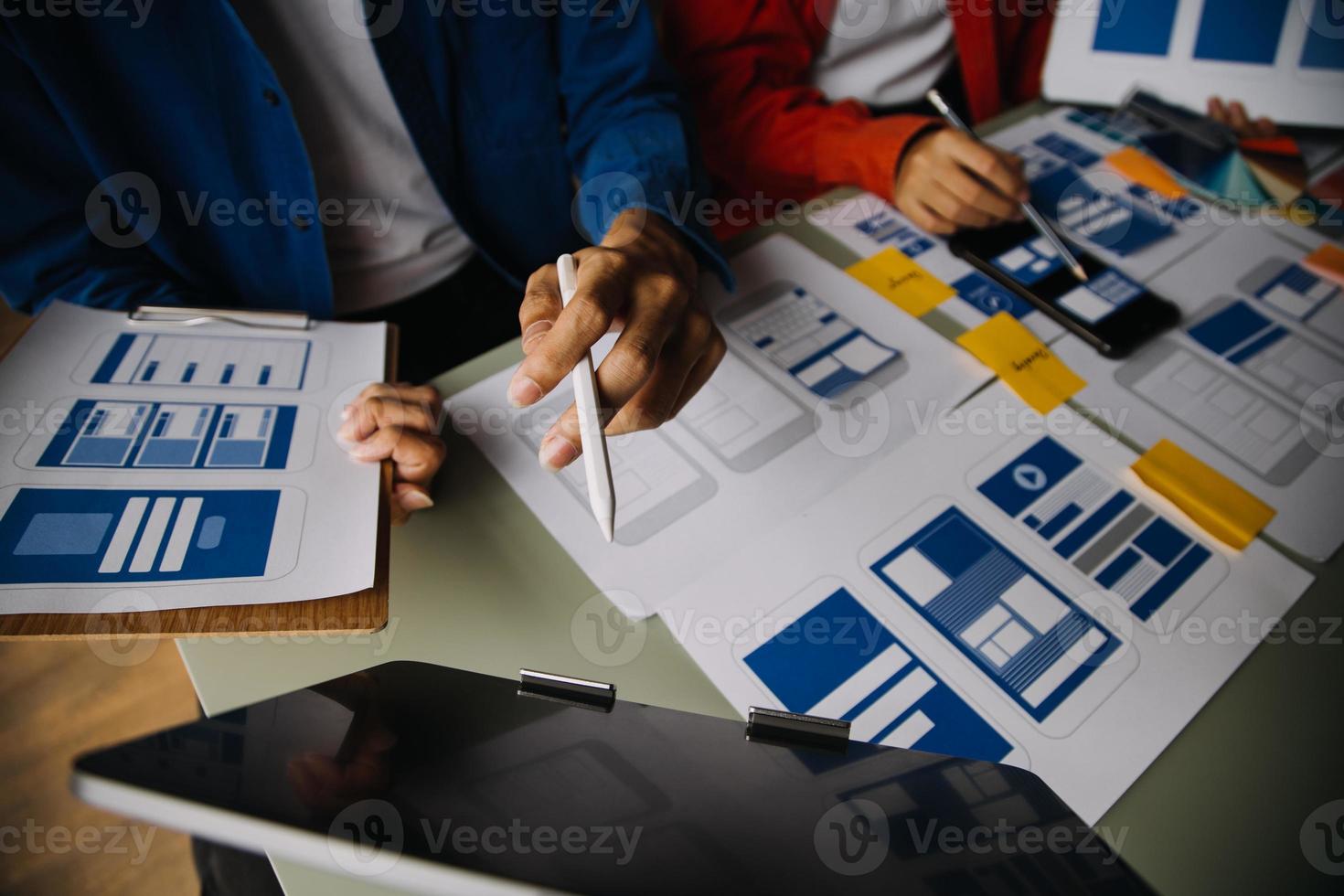 Close up ux developer and ui designer brainstorming about mobile app interface wireframe design on table with customer breif and color code at modern office.Creative digital development agency photo