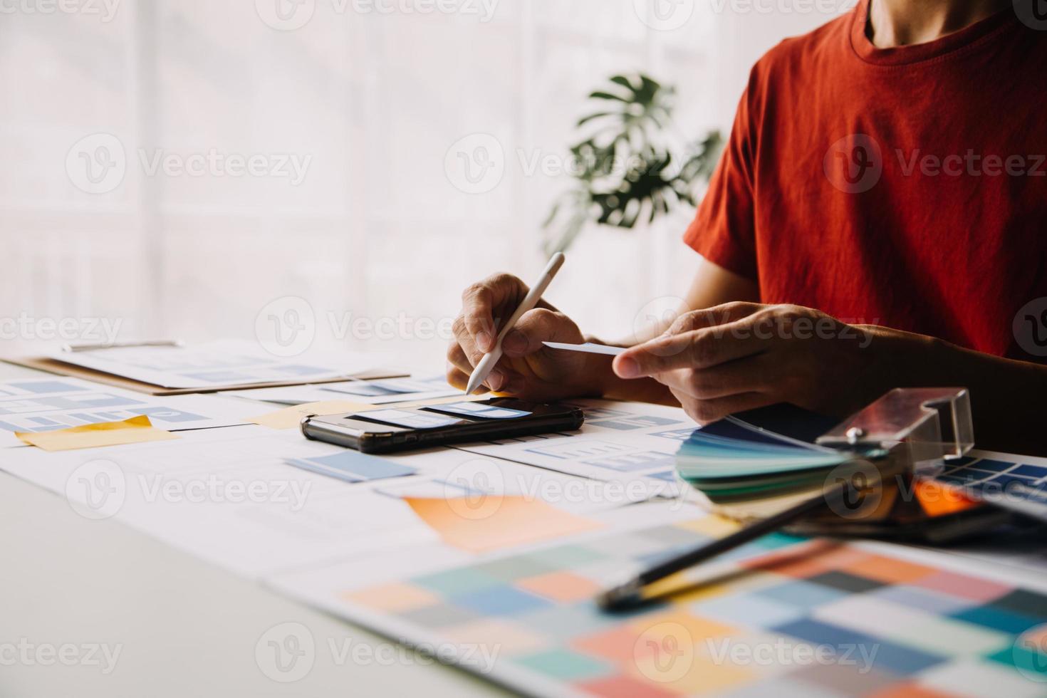 Close up ux developer and ui designer brainstorming about mobile app interface wireframe design on table with customer breif and color code at modern office.Creative digital development agency photo