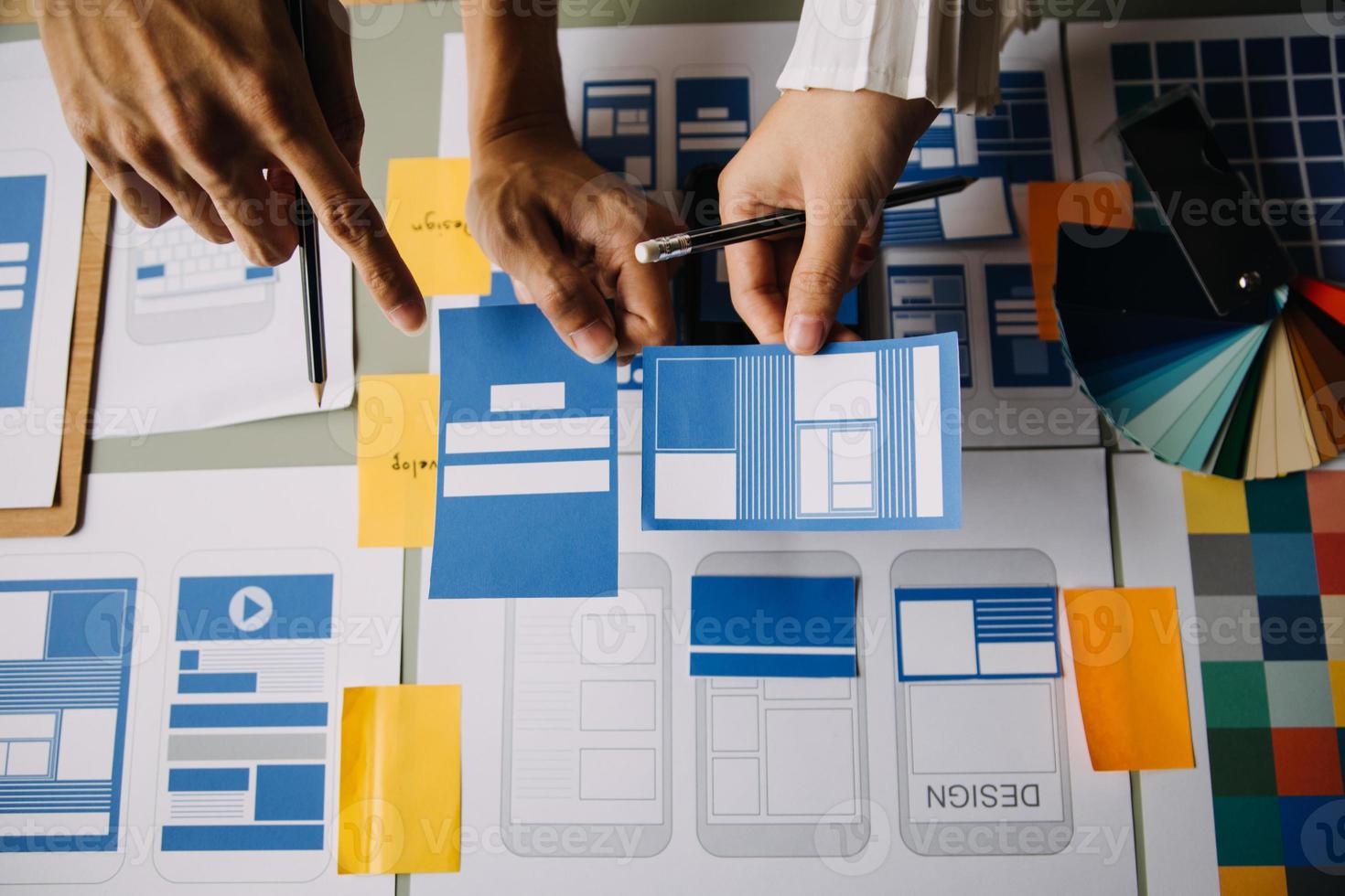 Close up ux developer and ui designer brainstorming about mobile app interface wireframe design on table with customer breif and color code at modern office.Creative digital development agency photo