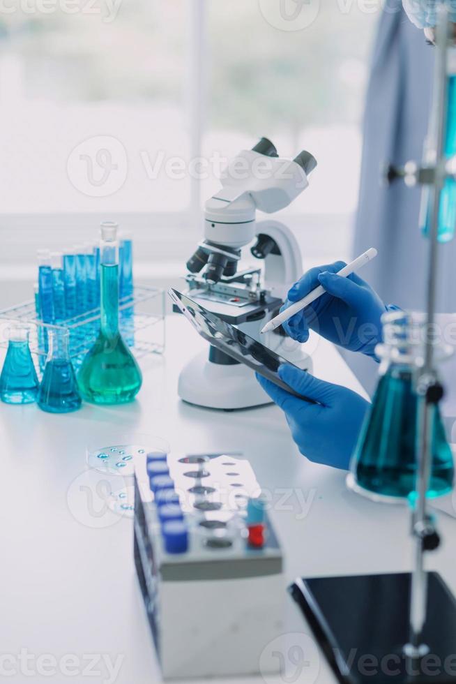 biochemical research scientist team working with microscope for coronavirus vaccine development in pharmaceutical research labolatory, selective focus photo