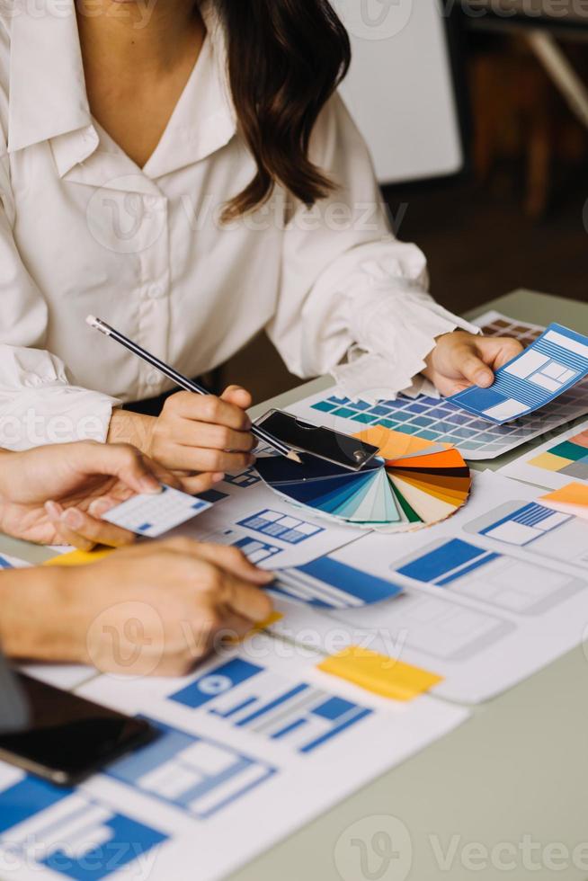 Close up ux developer and ui designer brainstorming about mobile app interface wireframe design on table with customer breif and color code at modern office.Creative digital development agency photo