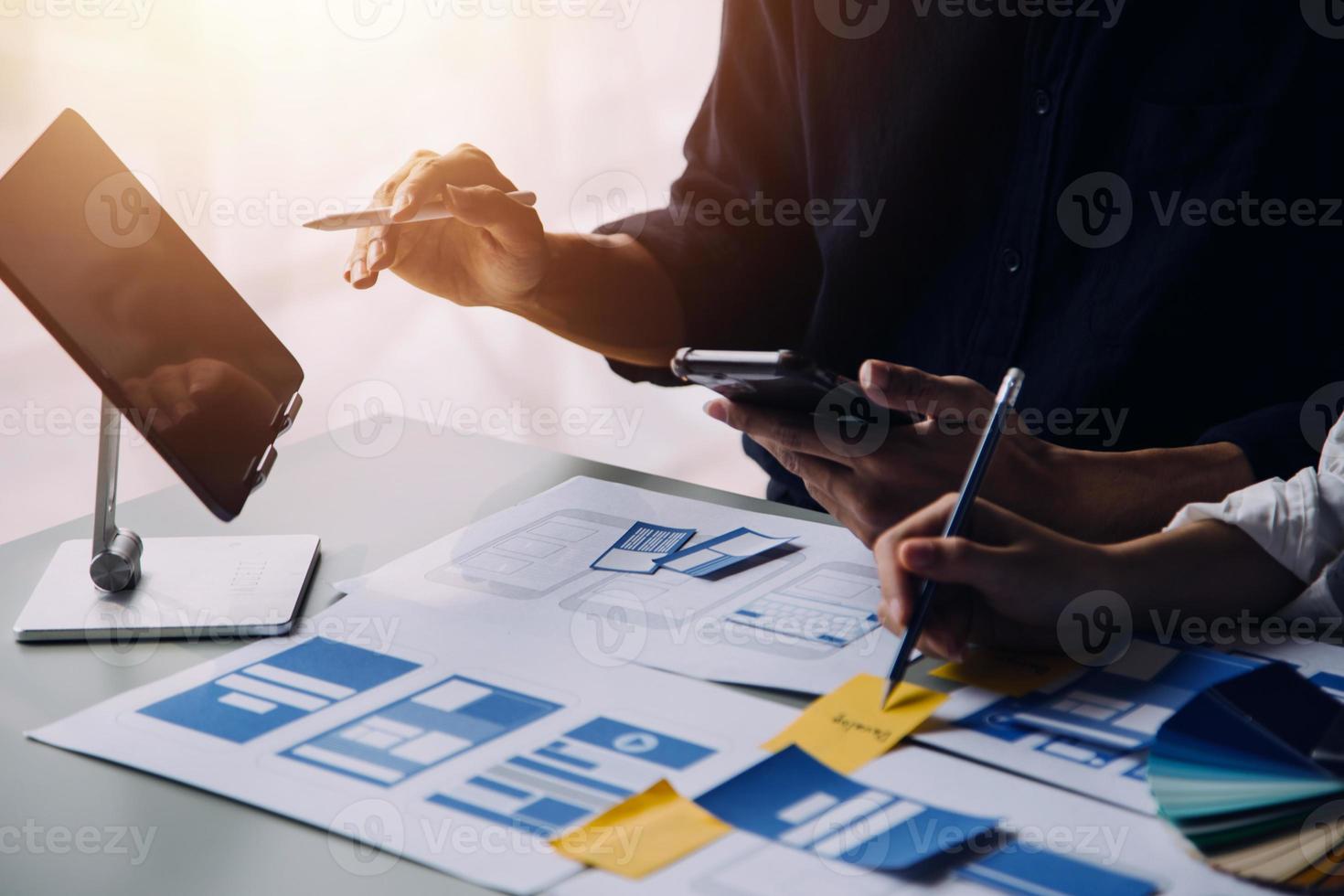 Close up ux developer and ui designer brainstorming about mobile app interface wireframe design on table with customer breif and color code at modern office.Creative digital development agency photo