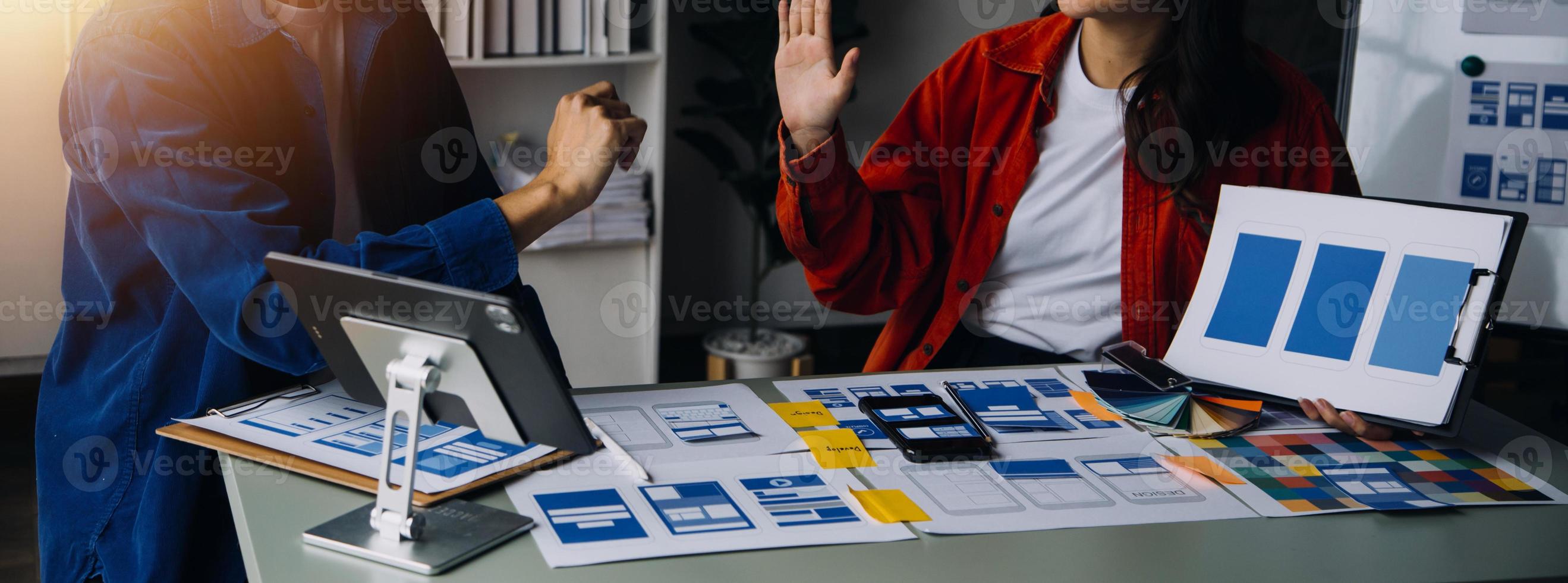 Close up ux developer and ui designer brainstorming about mobile app interface wireframe design on table with customer breif and color code at modern office.Creative digital development agency photo