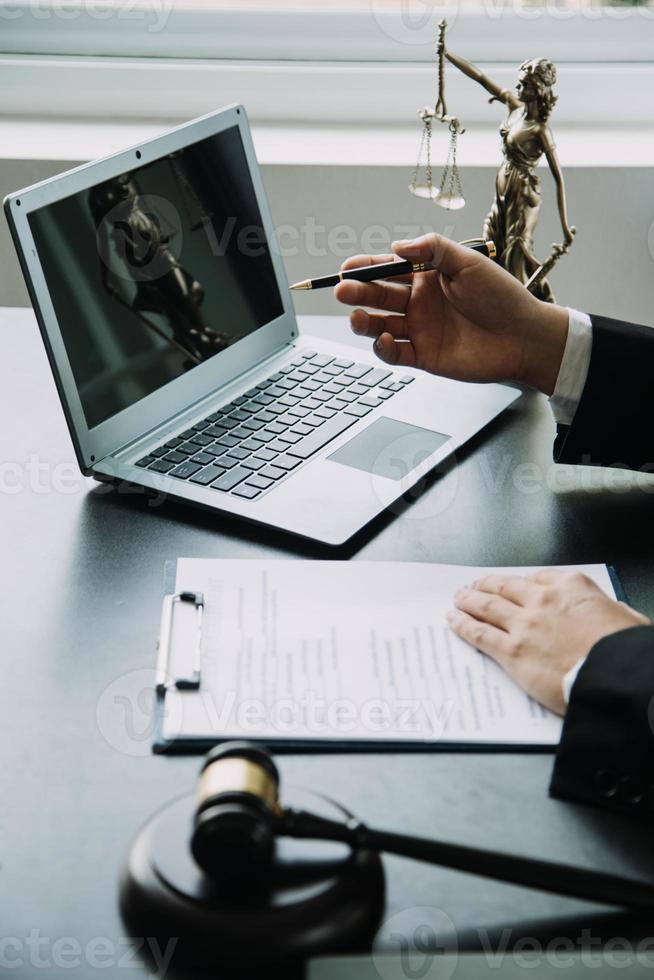 Justice and Law concept. Legal counsel presents to the client a signed contract with gavel and legal law or legal having team meeting at law firm in background photo