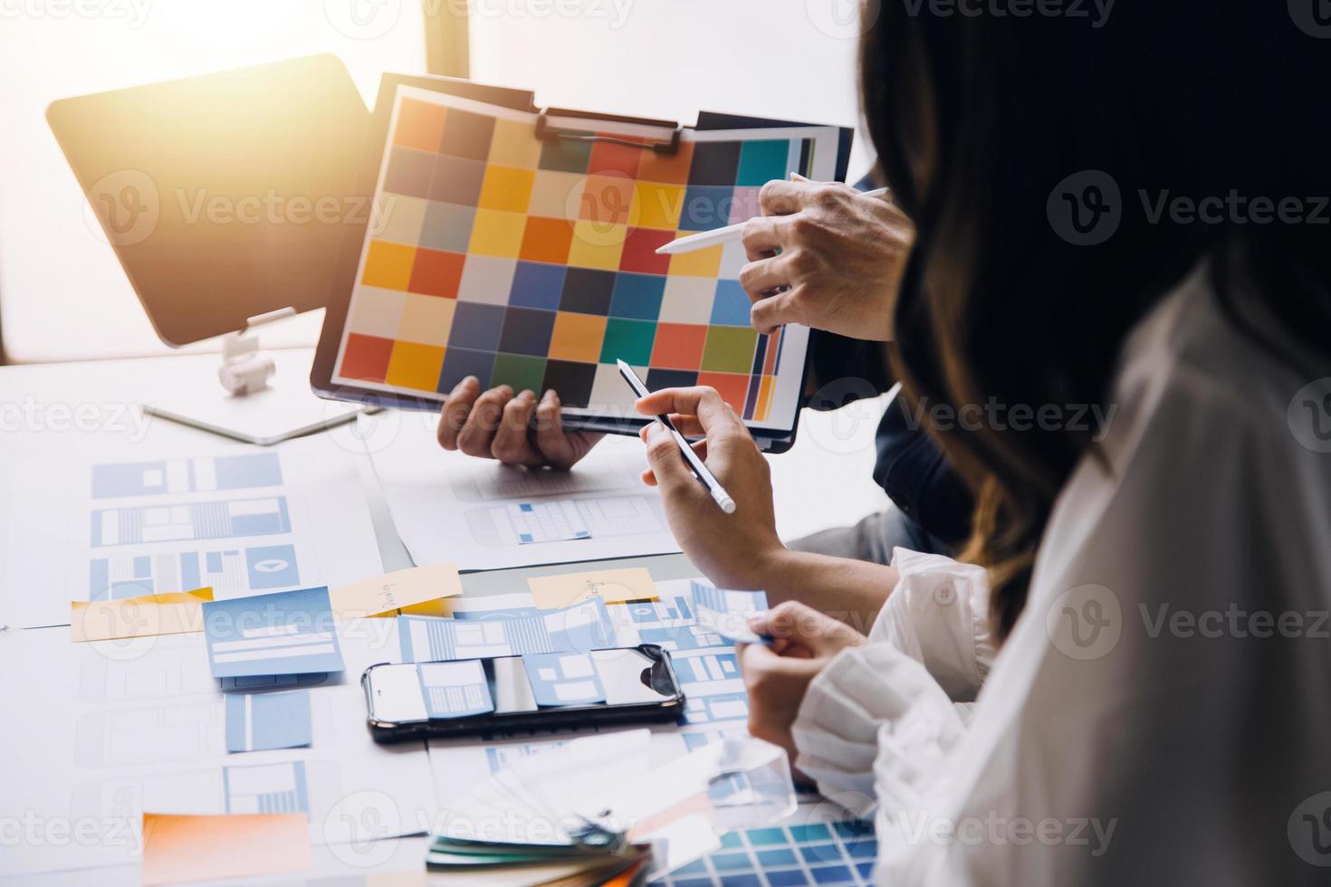 Close up ux developer and ui designer brainstorming about mobile app interface wireframe design on table with customer breif and color code at modern office.Creative digital development agency photo