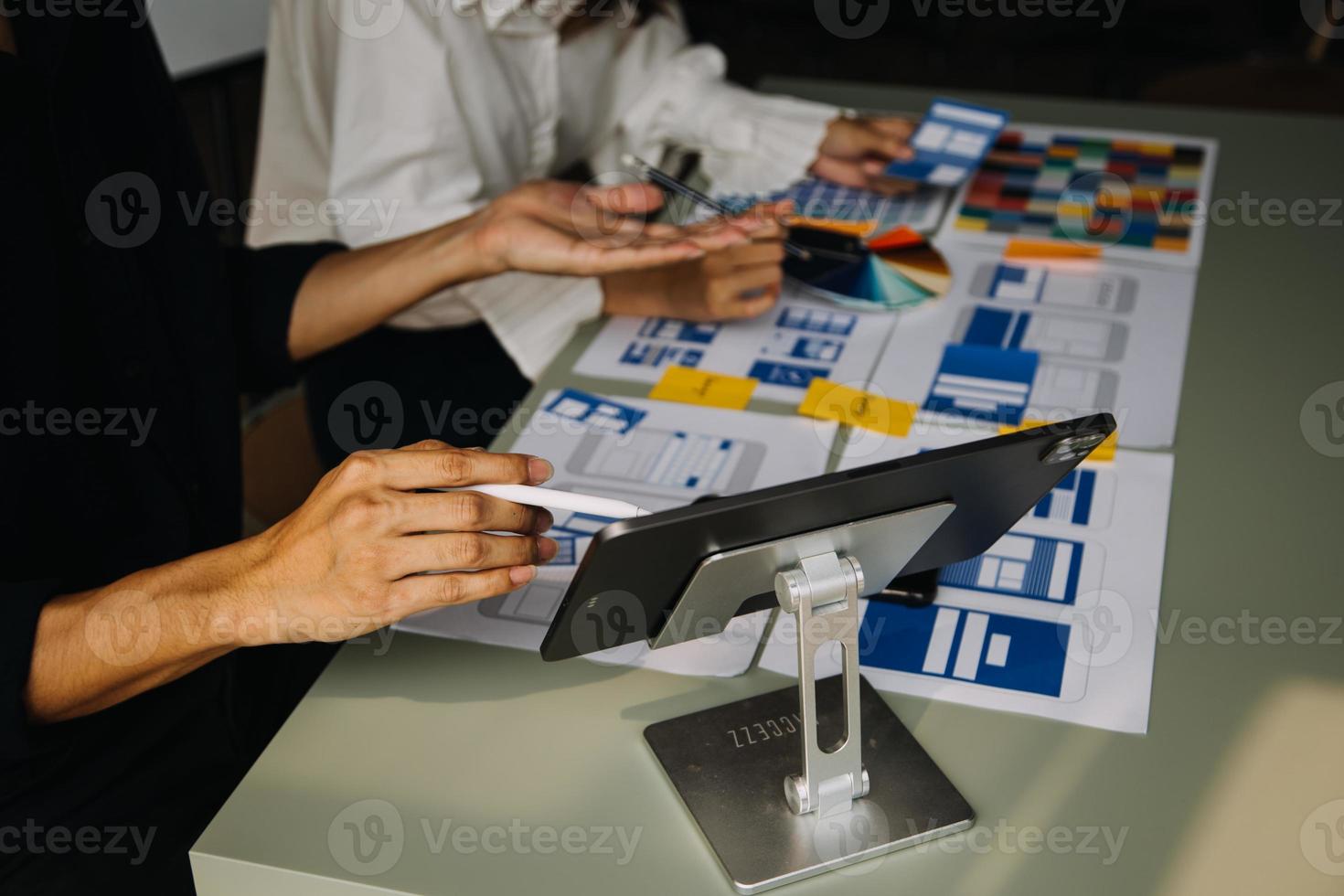 Close up ux developer and ui designer brainstorming about mobile app interface wireframe design on table with customer breif and color code at modern office.Creative digital development agency photo