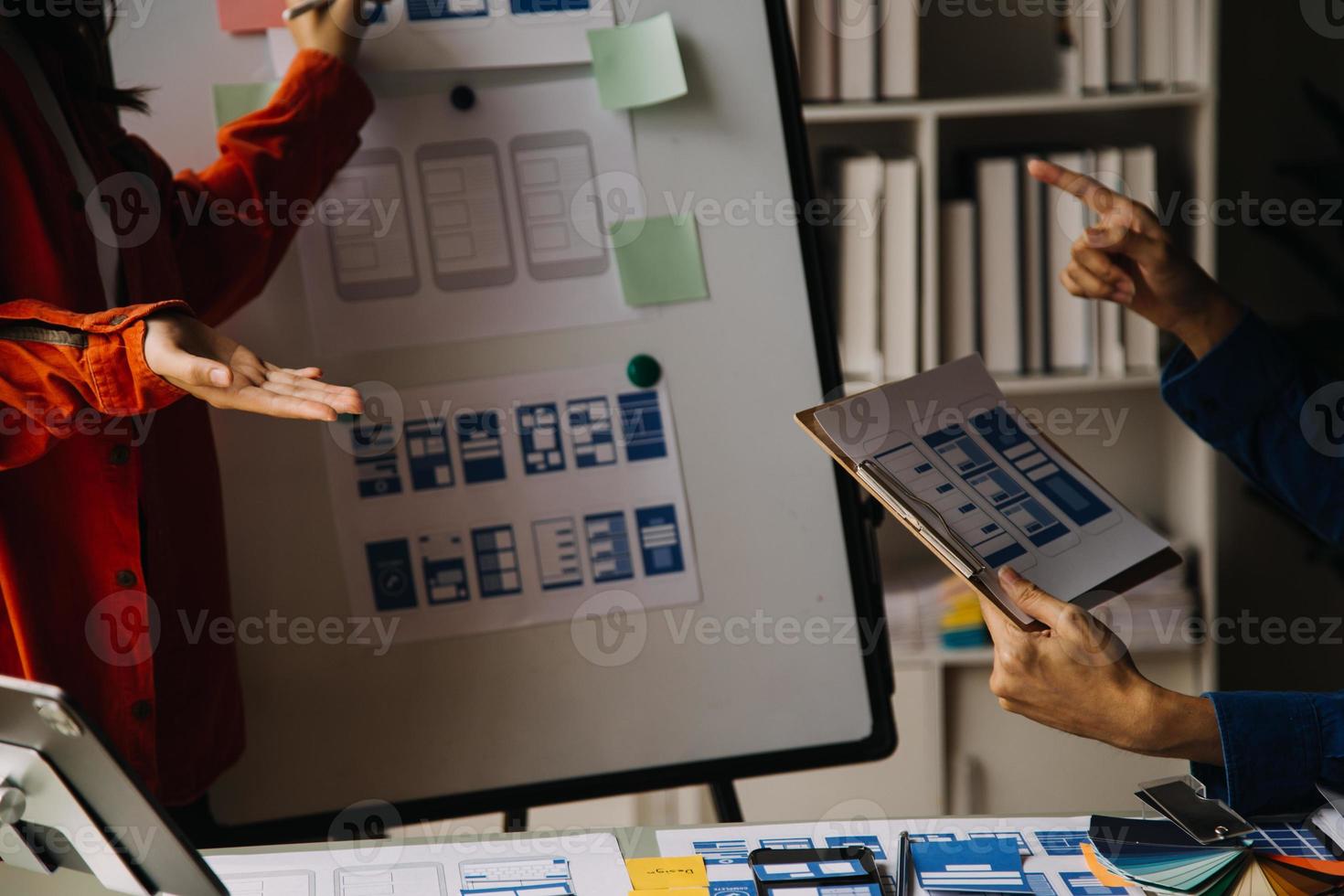 Close up ux developer and ui designer brainstorming about mobile app interface wireframe design on table with customer breif and color code at modern office.Creative digital development agency photo