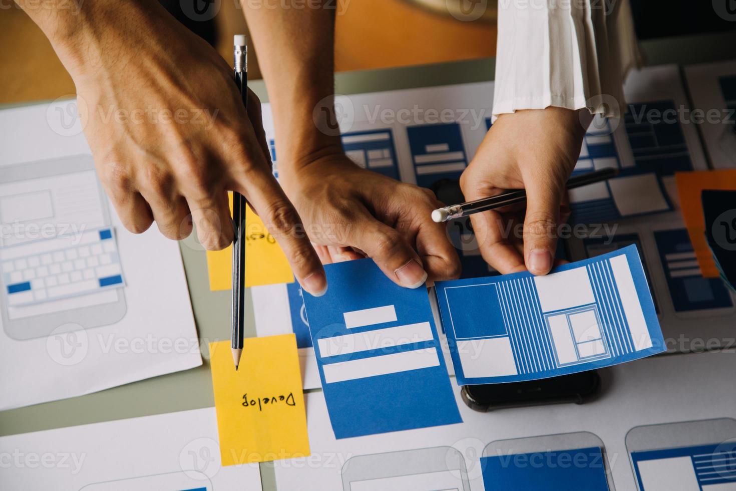 Close up ux developer and ui designer brainstorming about mobile app interface wireframe design on table with customer breif and color code at modern office.Creative digital development agency photo